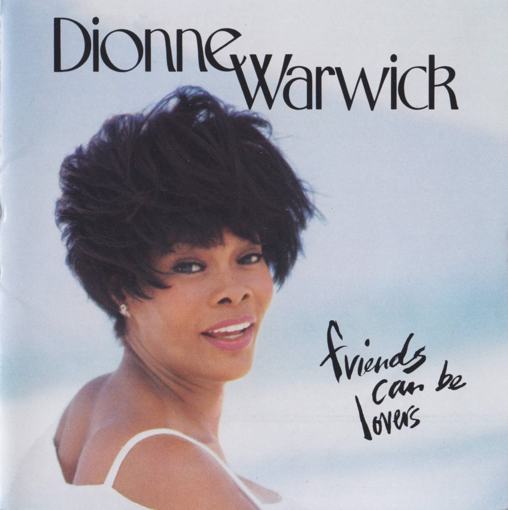 狄昂·華薇克《Friends Can Be Lovers》專輯 壁紙 — Dionne Warwick 身穿白色上衣，在柔和藍天背景下溫暖微笑，並帶有專輯標題文字。