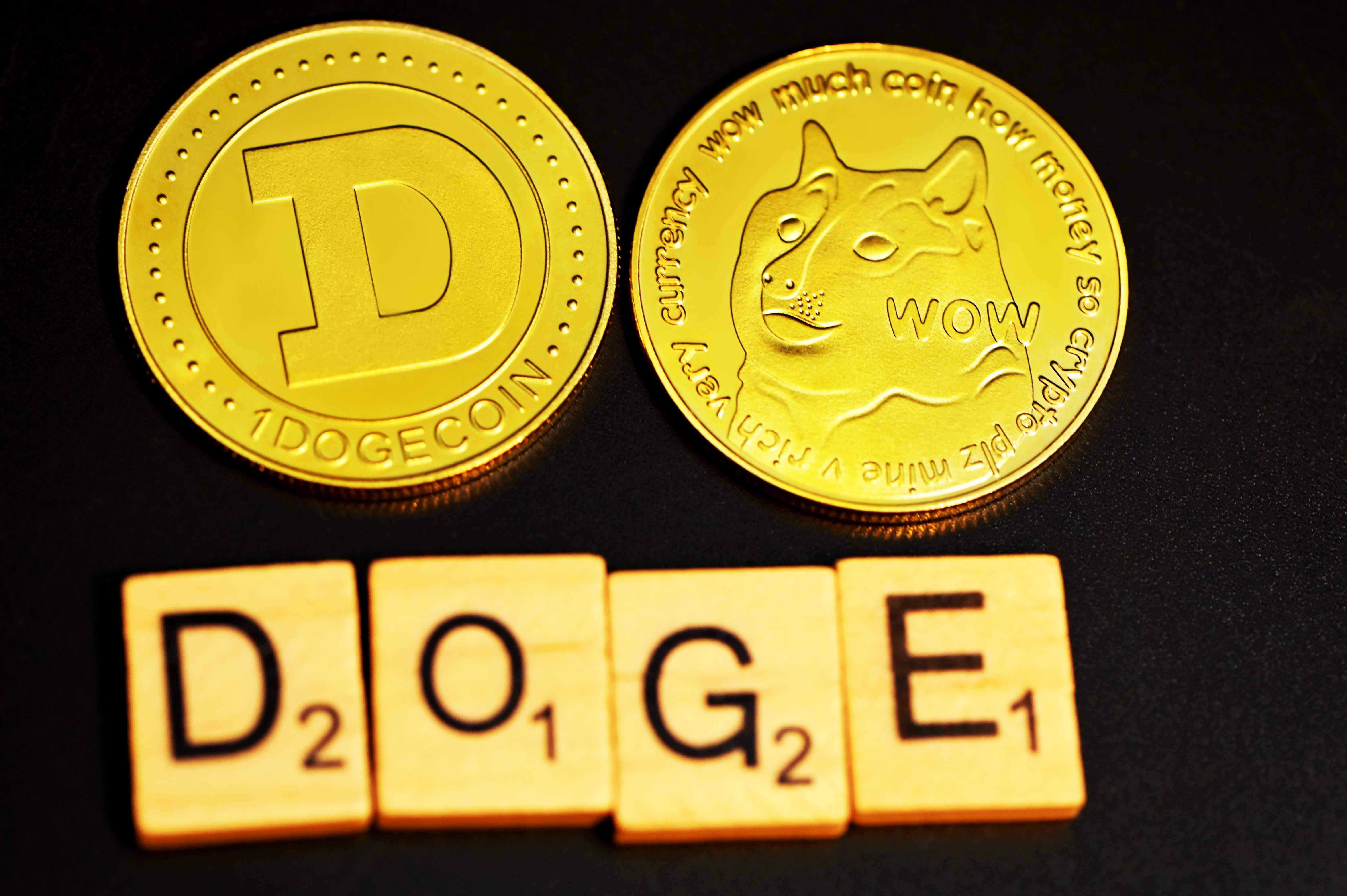 狗狗幣拼字遊戲方塊 壁紙 — 兩個金色 Dogecoin 代幣和拼出 DOGE 的 Scrabble 字母牌，在溫暖燈光下放置於深色表面上。