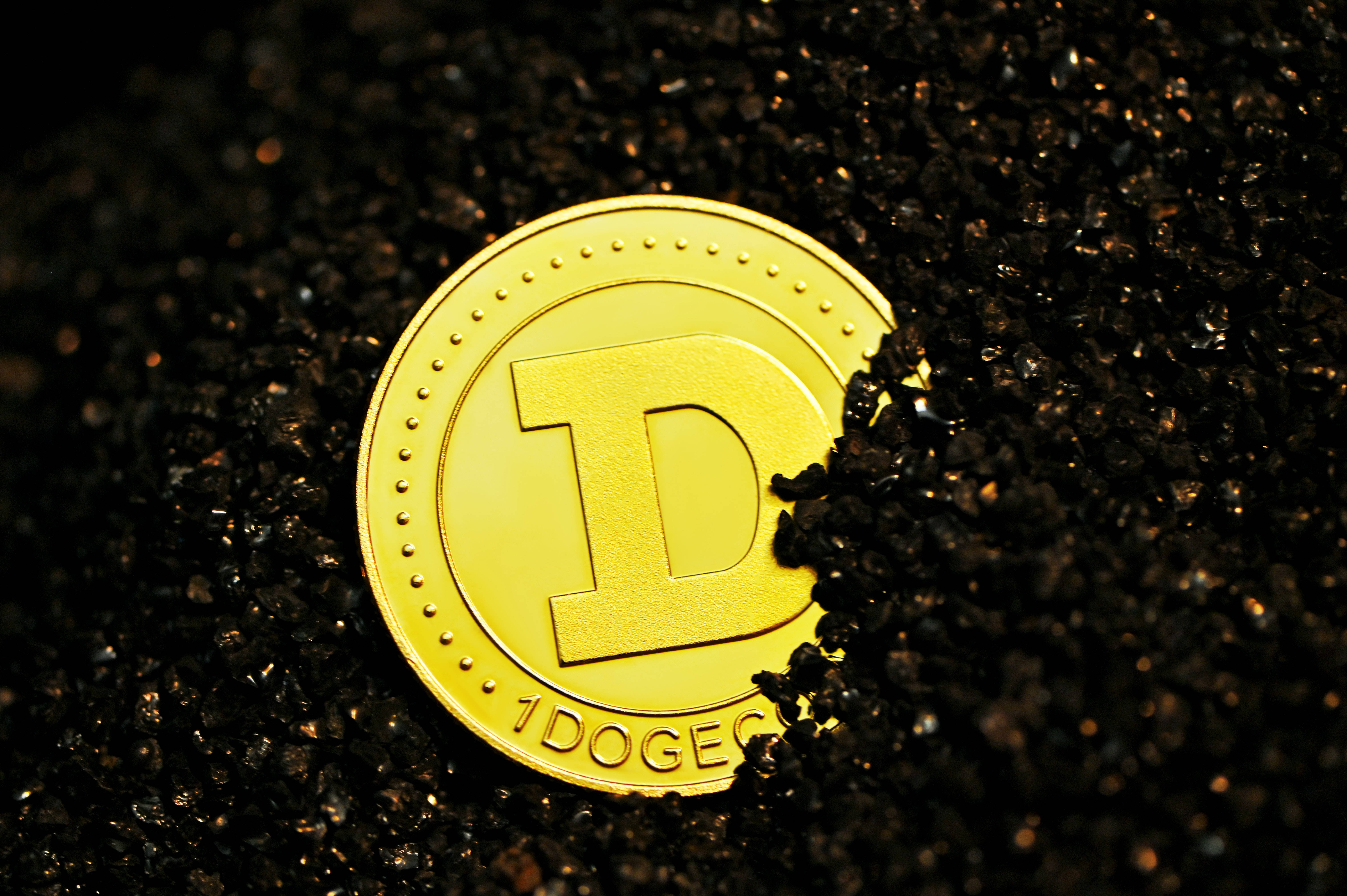 狗狗幣迷因加密貨幣 壁紙 — 一枚閃閃發光的金色狗狗幣部分埋在深色有紋理的土壤中，在聚焦照明下。