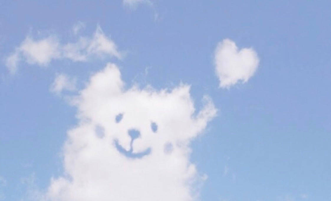 狗狗心形雲朵美學 壁紙 — 一朵蓬鬆的白雲形狀像微笑的熊，附近有一朵心形雲，襯著柔和的藍天。
