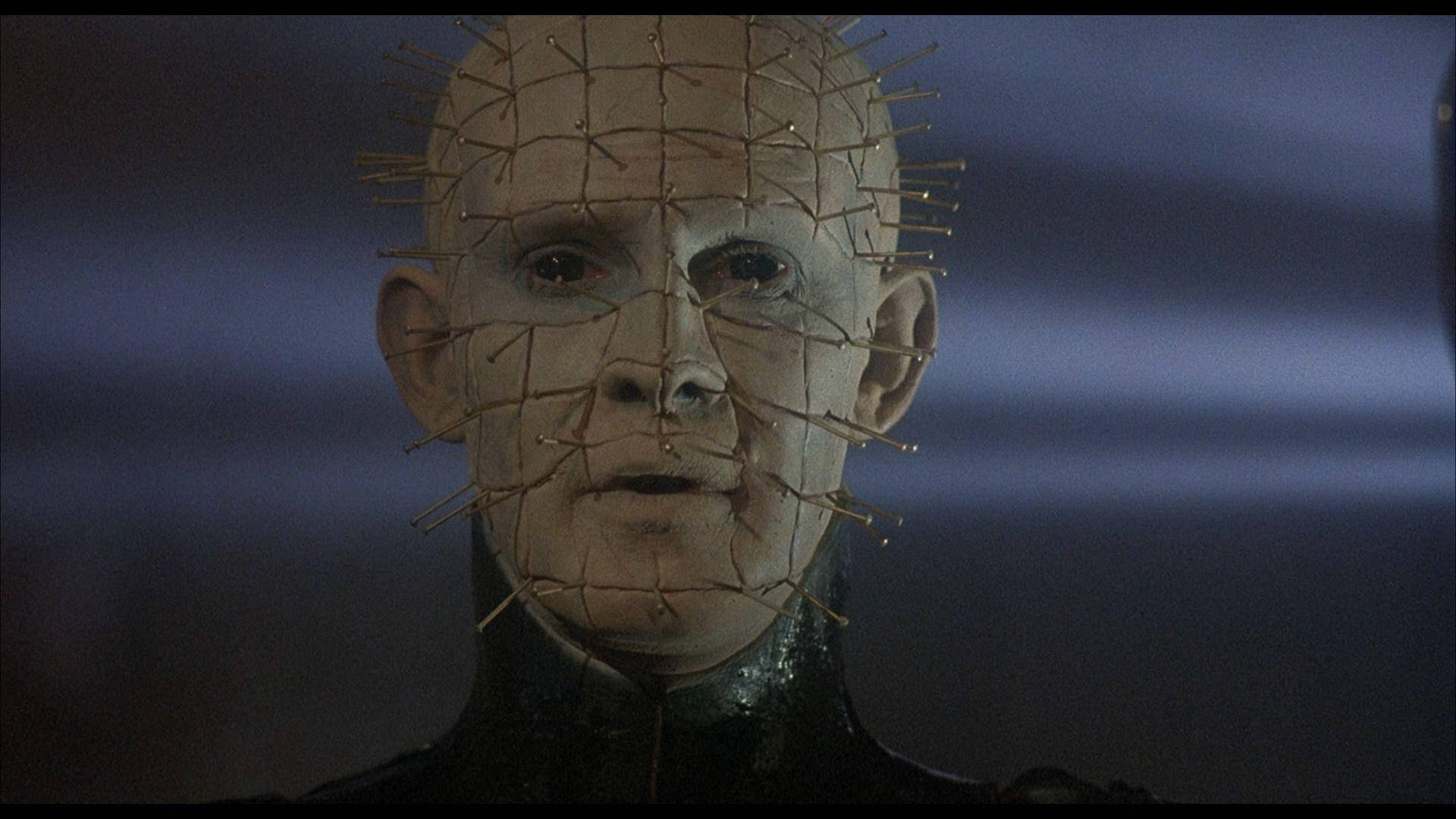 《猛鬼追魂》電影中的皮恩海德 壁紙 — Pinhead 嘅特寫，佢嘅面上嵌入咗針，背景係深藍色模糊嘅。