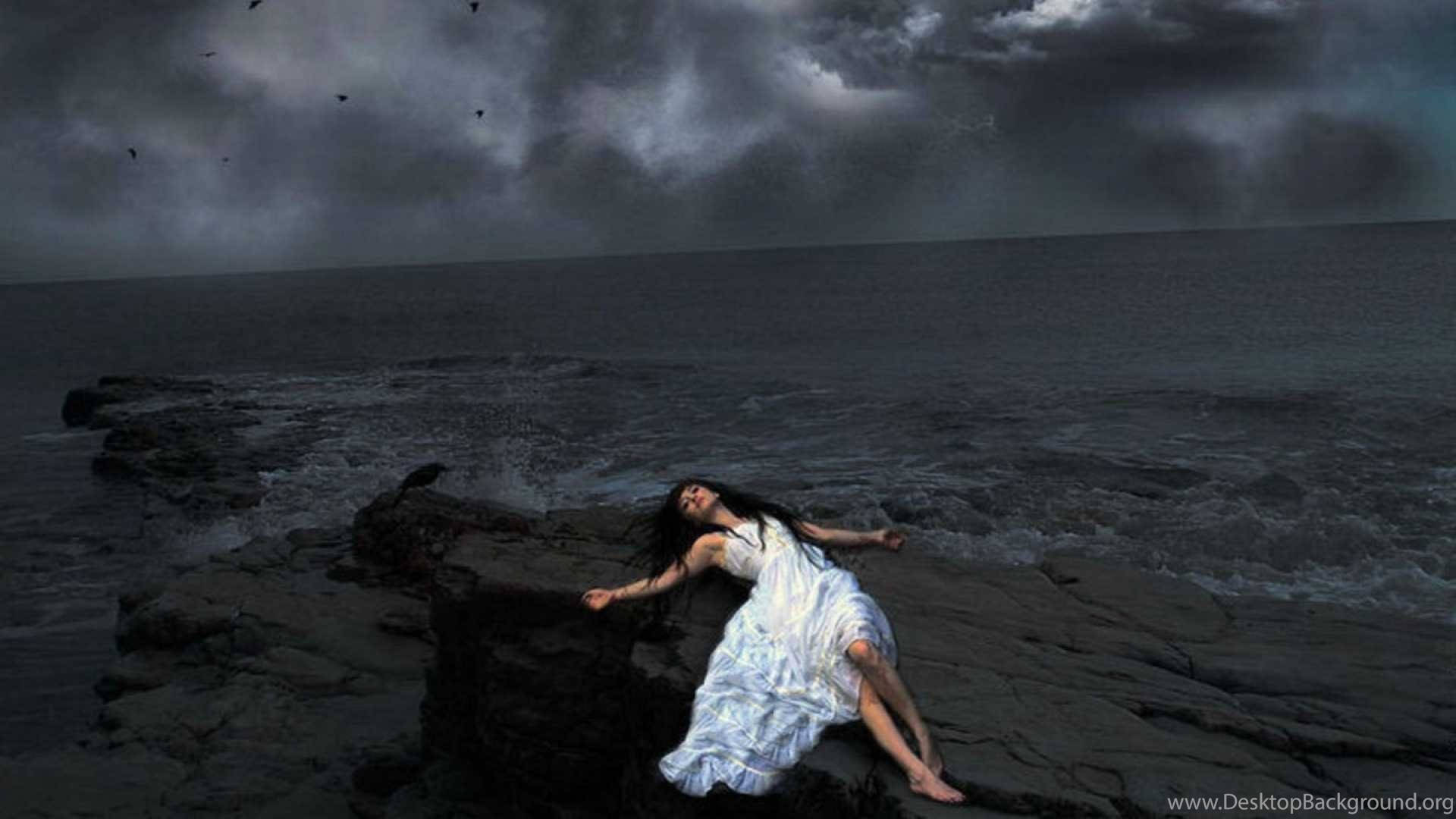 獨坐海邊的女子 壁紙 — 一名身穿白色連衣裙的女子躺在風暴般的海岸岩石上，烏雲和鳥類籠罩在頭頂。