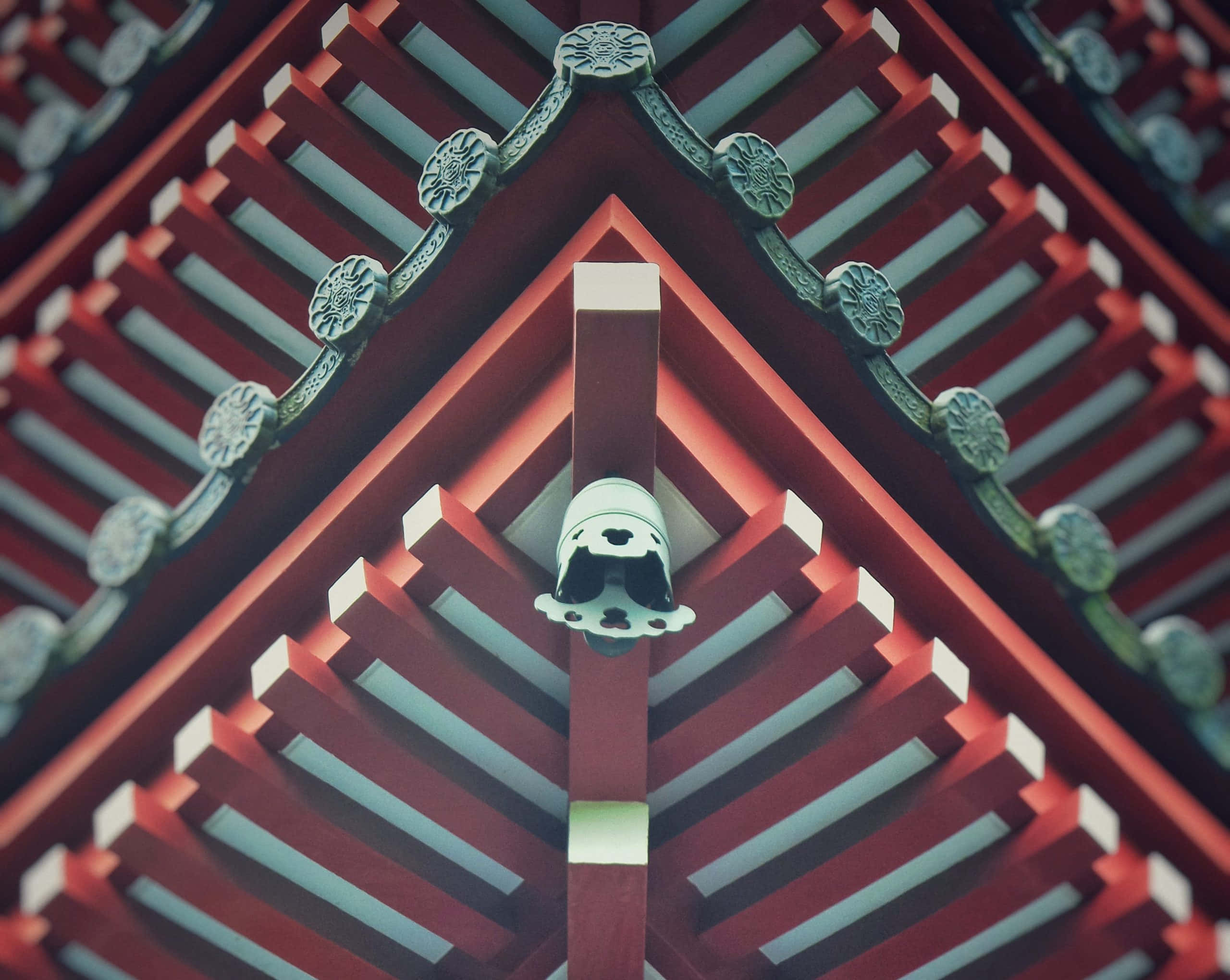 獨特圖案的迷人彩色圓圈 壁紙 — 傳統紅色木屋頂的特寫，帶有華麗的綠色支架和中央裝飾尖頂。
