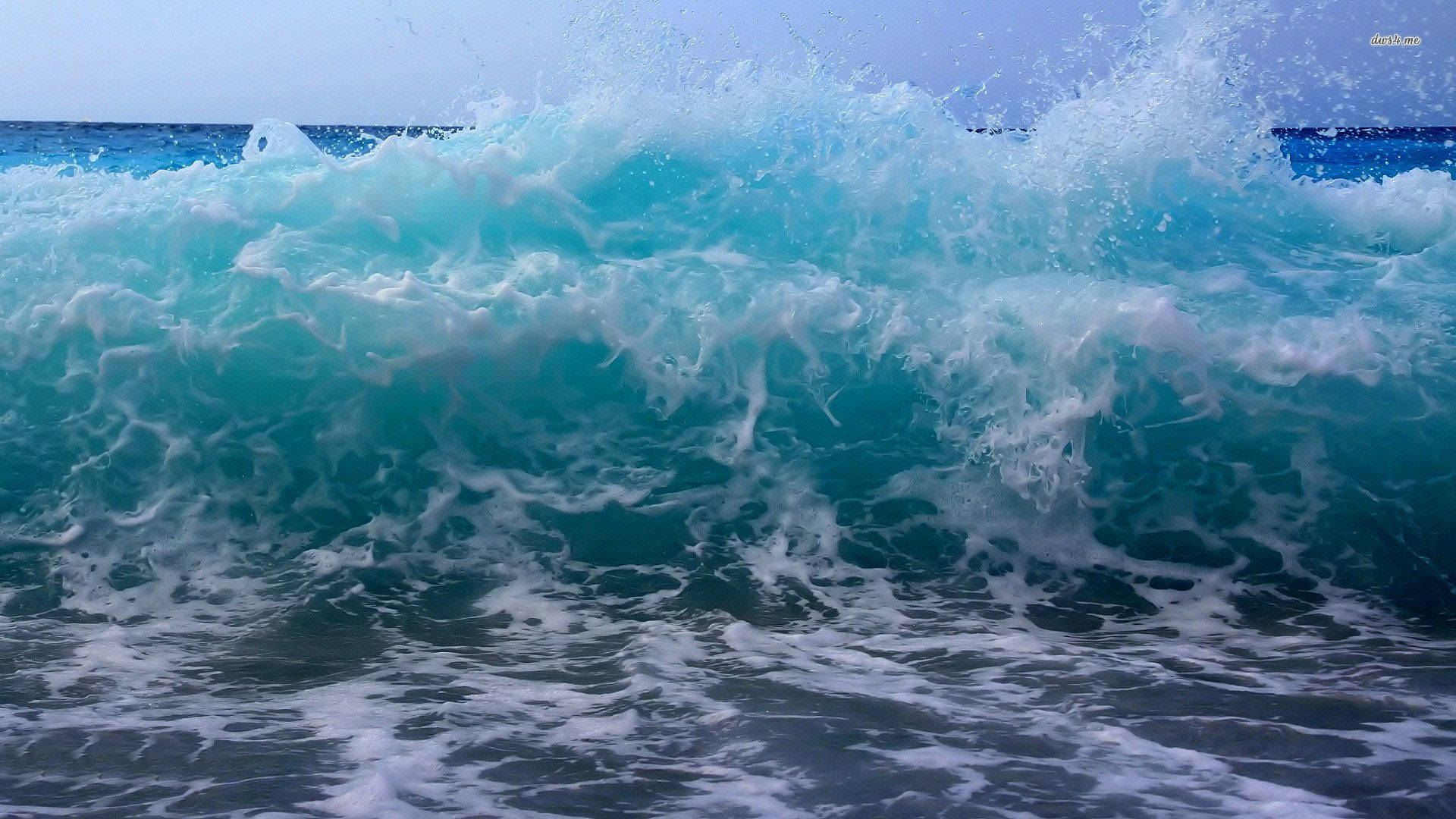 一道拍打海岸的藍綠色海浪，帶有白色泡沫。