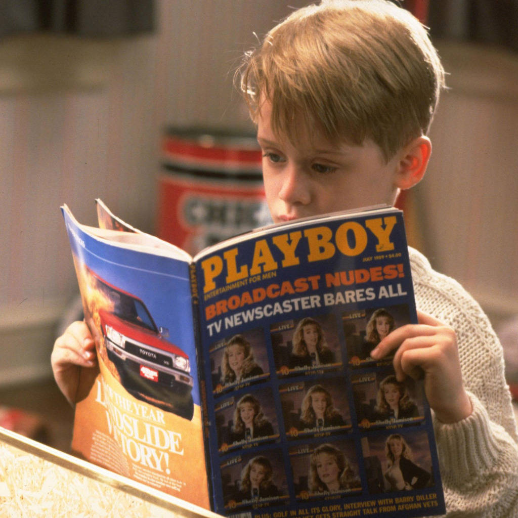 小男孩在室內閱讀復古的《Playboy》雜誌。