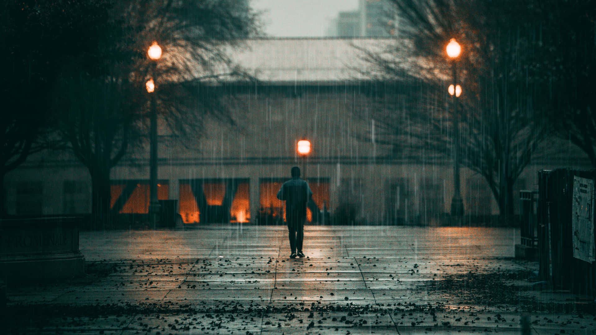 一個人在夜晚的城市中，在發光的街燈下獨自走在雨中。
