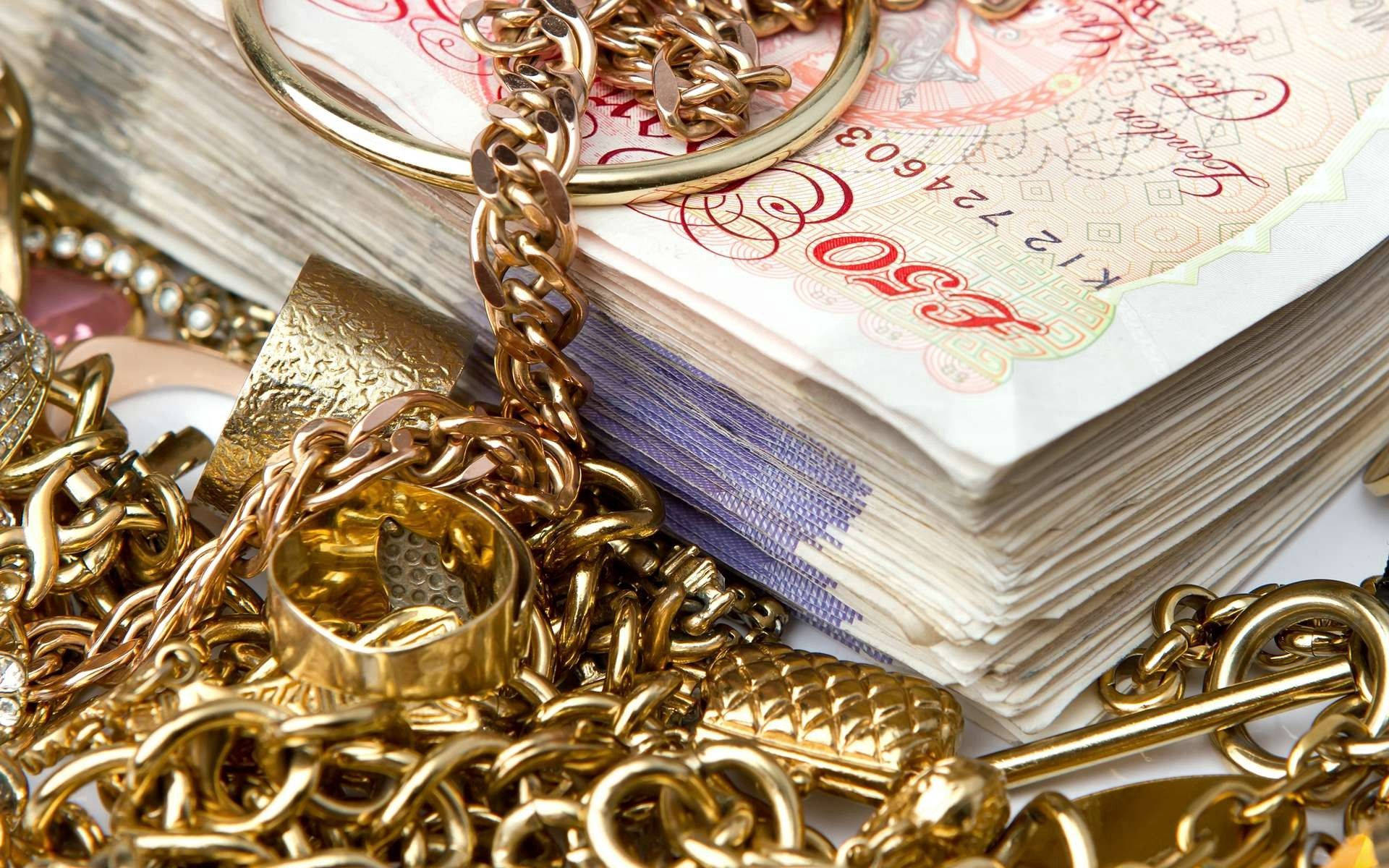 一疊英國50英鎊鈔票與金鏈和戒指混合。