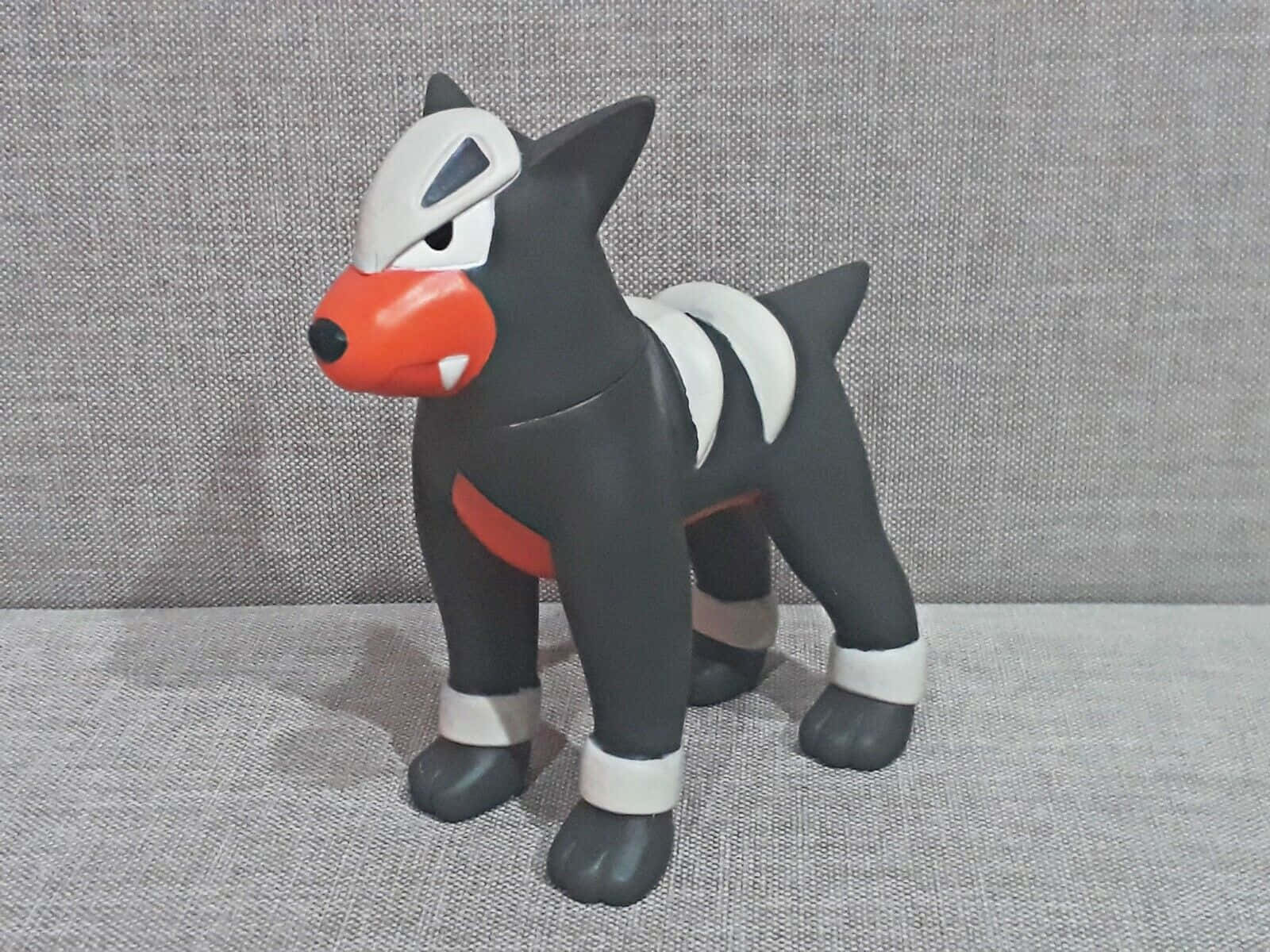 灰色布料上的黑色、白色和橙色 Houndour 寶可夢公仔。