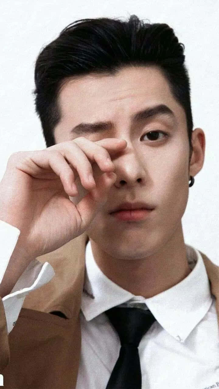 穿西裝打領帶的年輕男子，在攝影棚肖像中手靠近眼睛