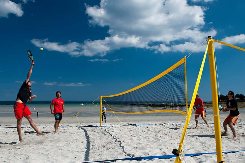 Beach Tennis 桌布 壁紙 — 玩家在晴朗藍天和蓬鬆白雲下進行沙灘網球比賽。