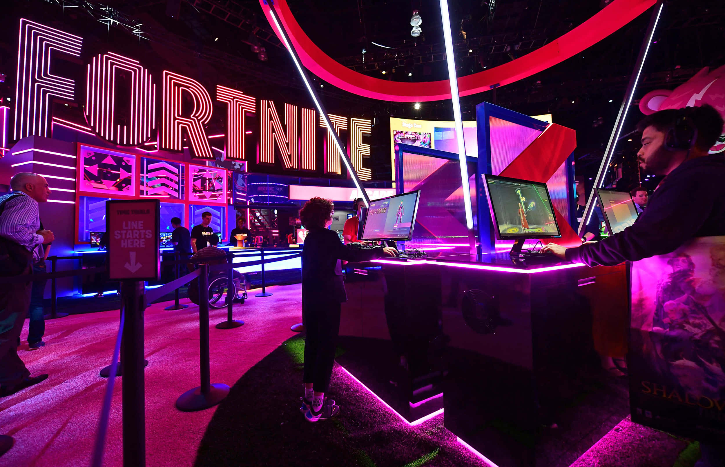 Gaming Conventions 桌布 壁紙 — 玩家在發光的粉紅色和藍色霓虹燈下於Fortnite遊戲活動中競爭。