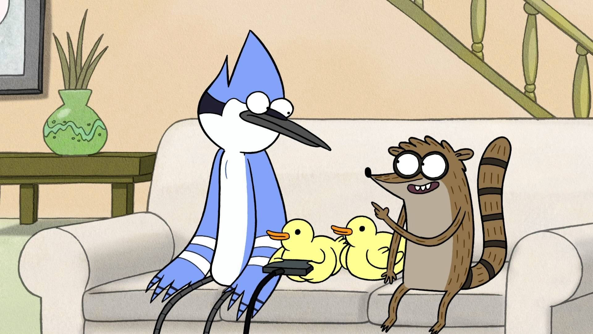 玩遊戲的《Regular Show》鴨子 壁紙 — 一隻藍鳥和一隻浣熊坐在沙發上，旁邊有橡膠鴨子，浣熊興奮地指著。