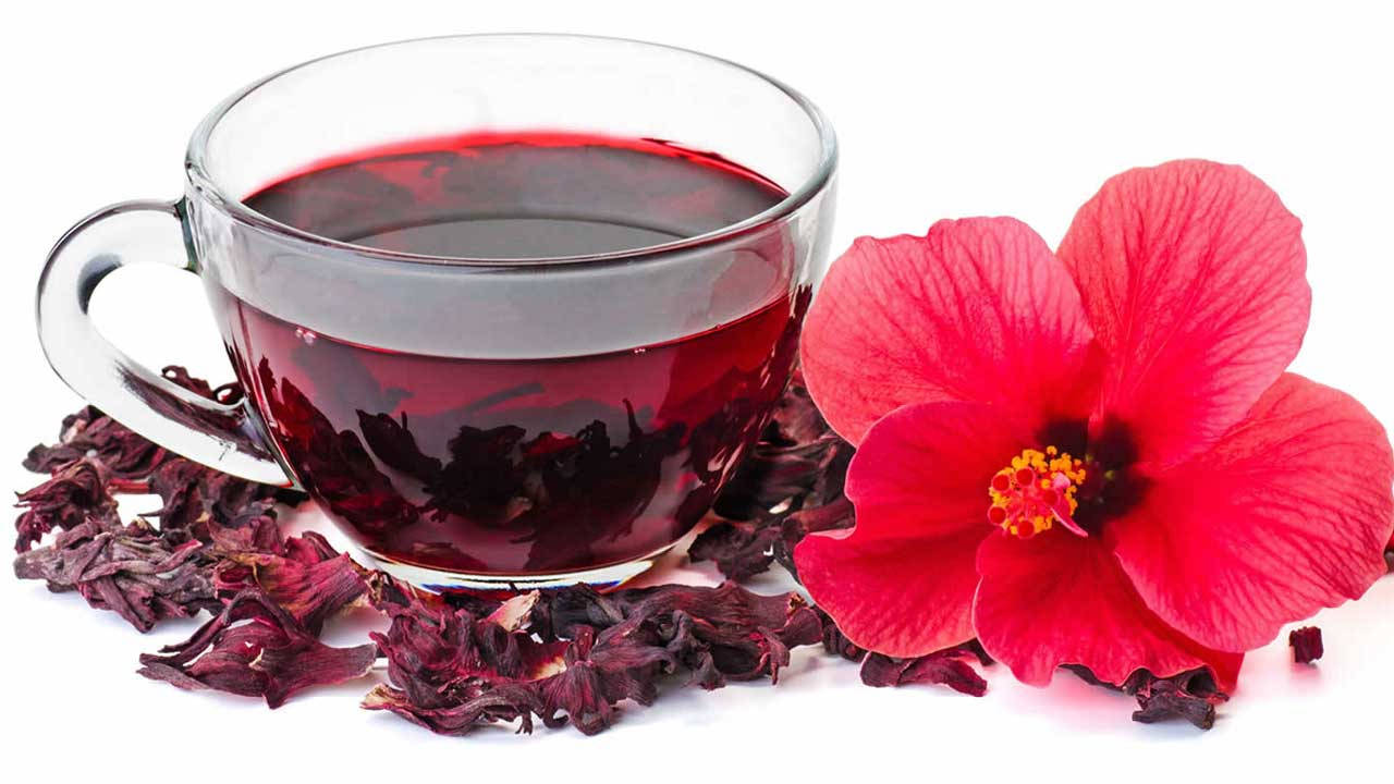 一杯洛神花茶配以新鮮的紅色洛神花和乾花瓣。