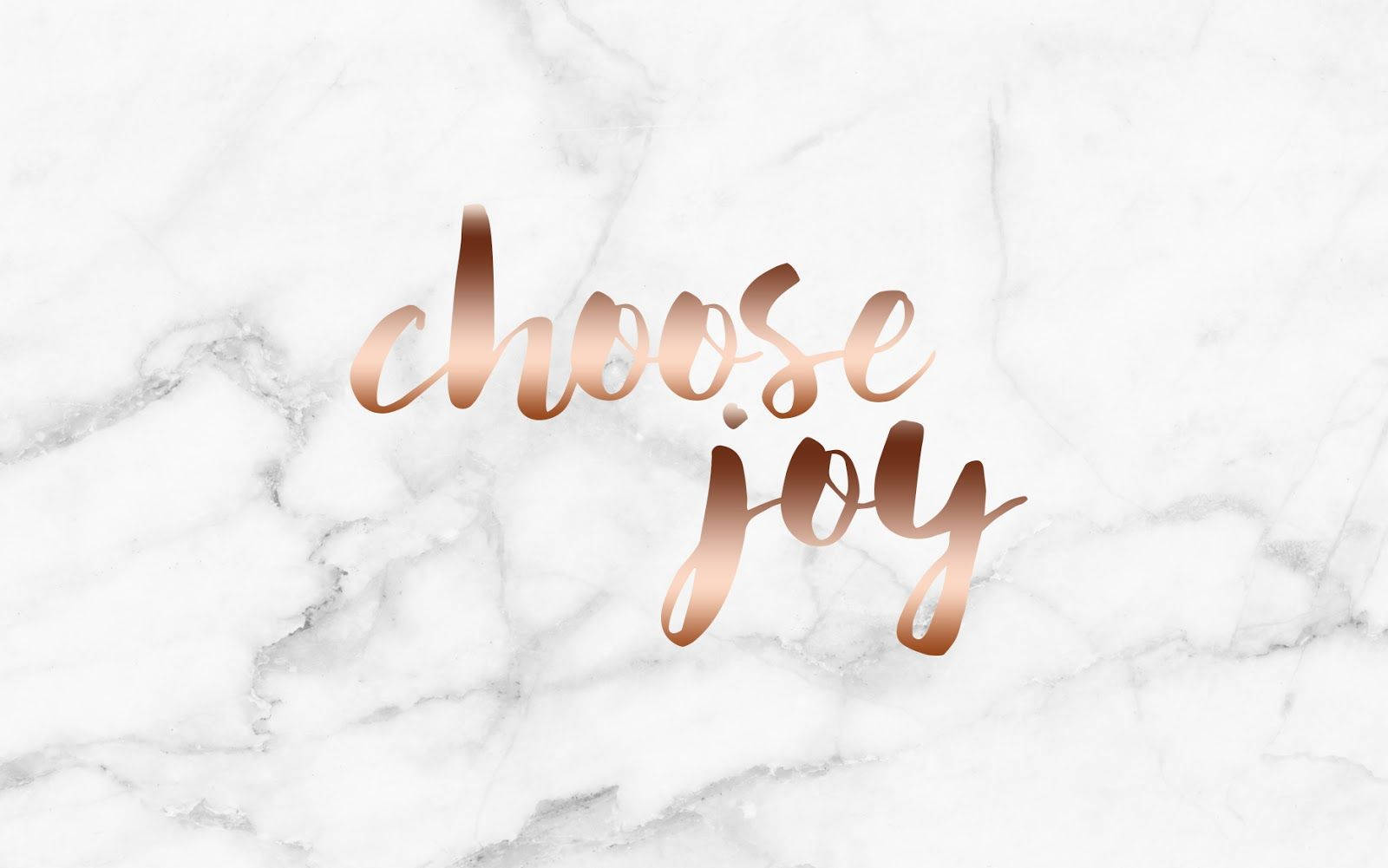 白色大理石背景上的玫瑰金色字體「choose joy」