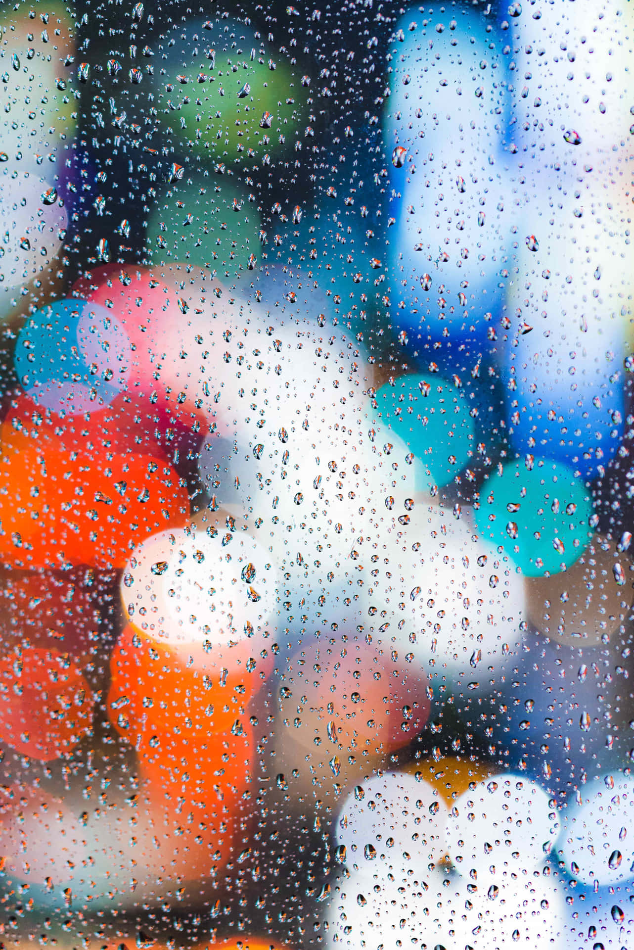 玻璃上的雨滴，背後是模糊多彩的城市燈光。