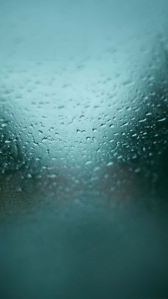玻璃上雨滴紋理 壁紙 — 雨滴依附在玻璃表面，將藍綠色的戶外景色模糊成一層柔和、充滿氛圍的薄霧。