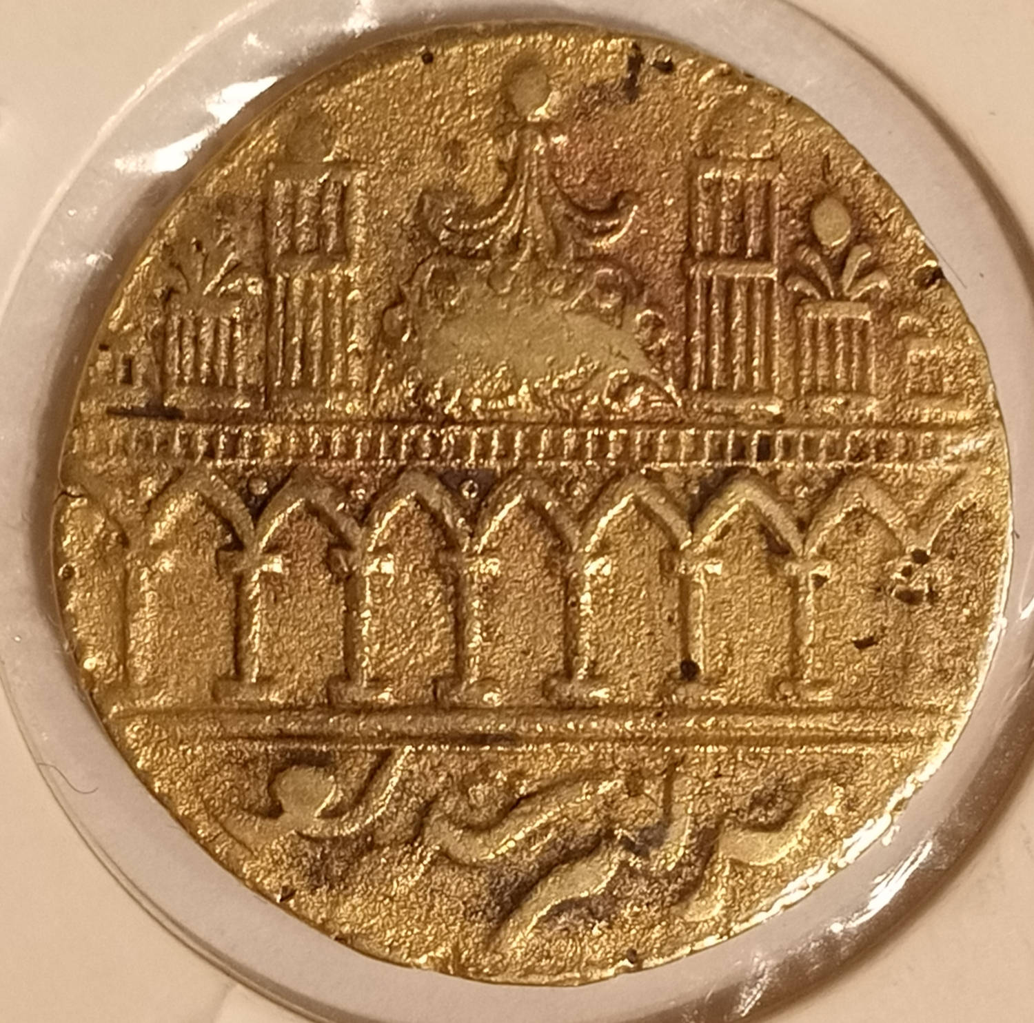 Madina Sharif 桌布 壁紙 — 玻璃下古老金幣的特寫，帶有複雜的阿拉伯文字和建築雕刻。