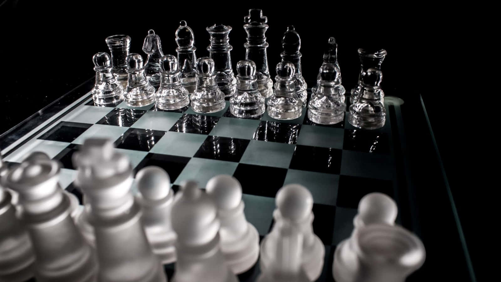 Chessboard 桌布 壁紙 — 玻璃國際象棋棋子放在反光棋盤上，淺景深，黑色背景。