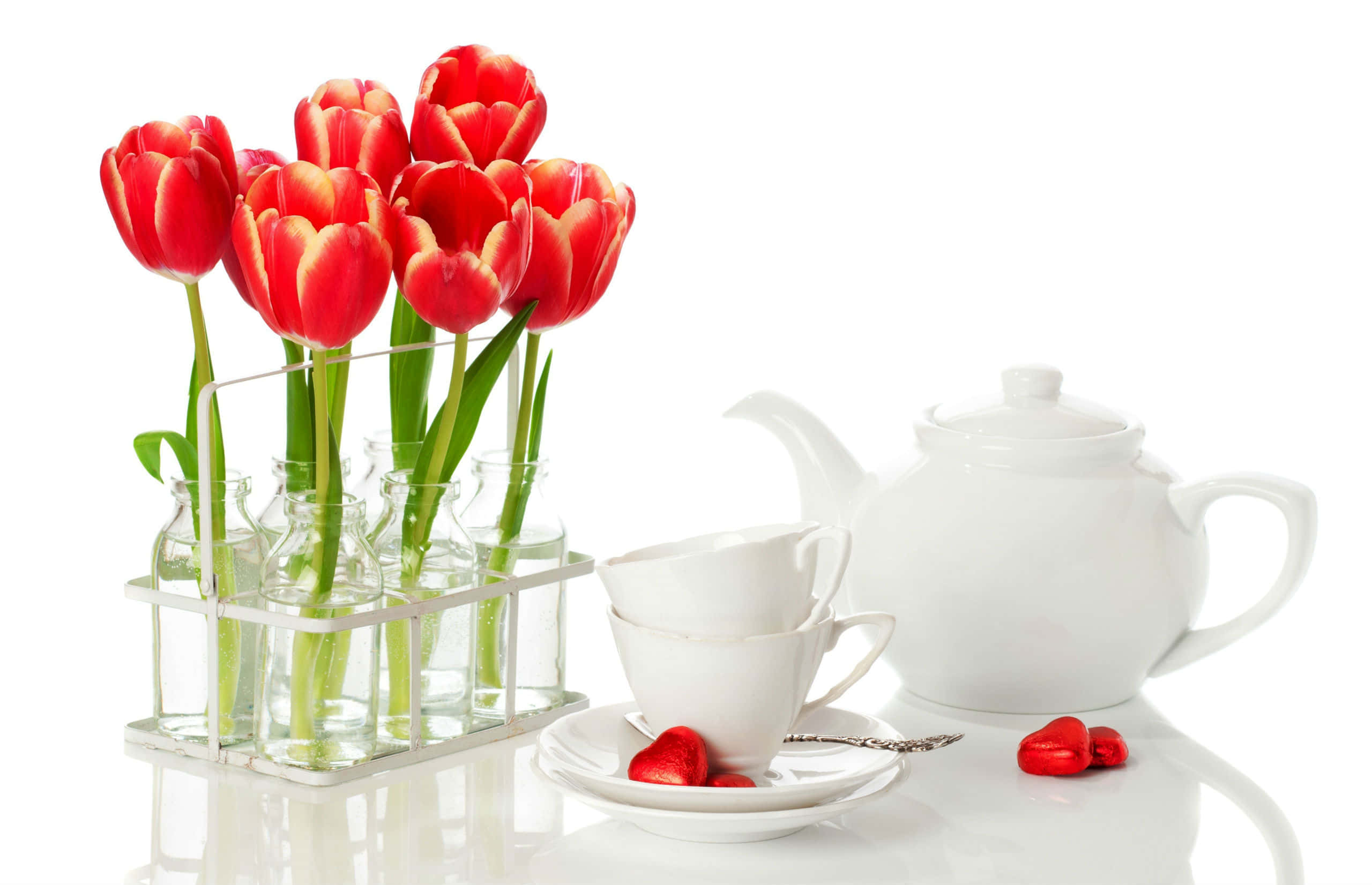 Floral Tea 桌布 壁紙 — 玻璃瓶中的鮮紅色鬱金香旁邊放著白色茶壺和杯子，在反光表面上還有心形糖果。