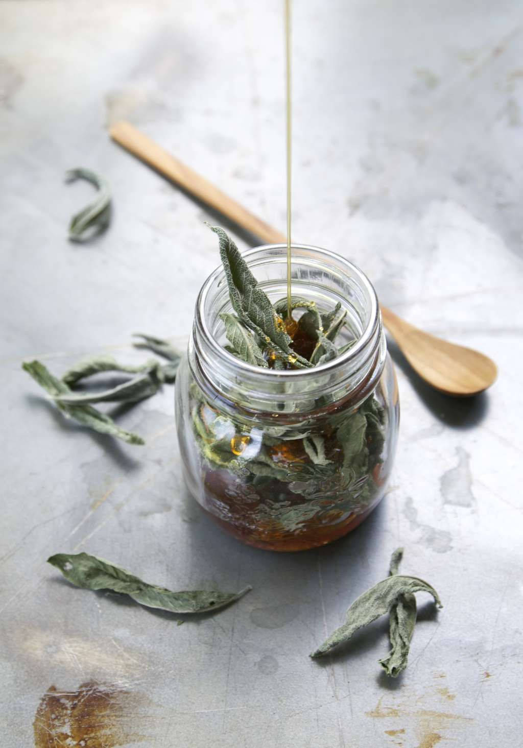 玻璃罐裝發酵 sage 壁紙 — 金色蜂蜜滴入裝滿乾燥鼠尾草葉的玻璃罐中，置於質樸的金屬表面上。