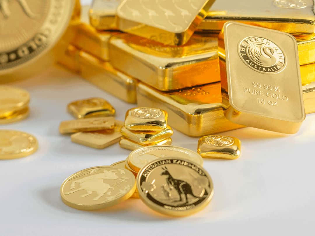 珀斯鑄幣廠黃金幣 壁紙 — 閃閃發光的金條堆和散落的澳洲金幣在潔白的表面上反射光線。
