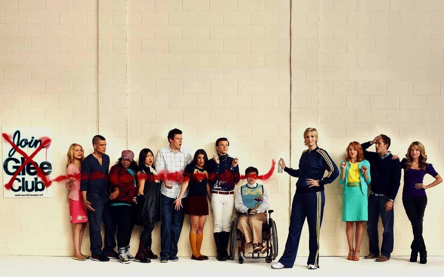 珍妮·蓮絲《歡樂合唱團》塗鴉海報 壁紙 — Cast of Glee 自信地擺姿勢，背景是米色磚牆，旁邊有一個被紅色噴漆劃掉的「Join Glee Club」標誌。