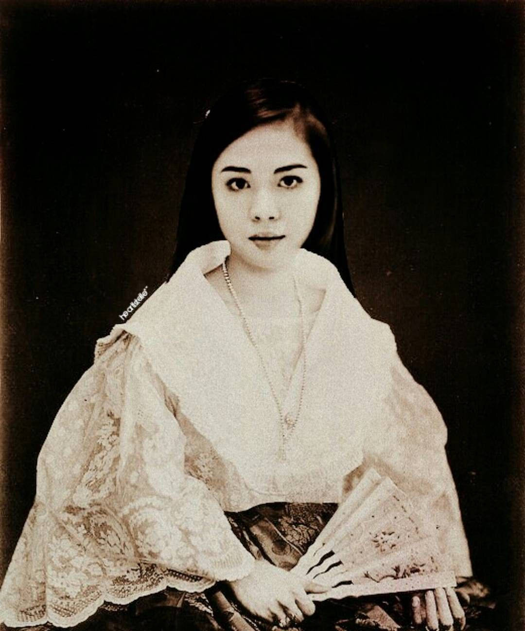 一位穿著復古蕾絲服飾的女子在黑暗的攝影棚肖像中手持扇子。