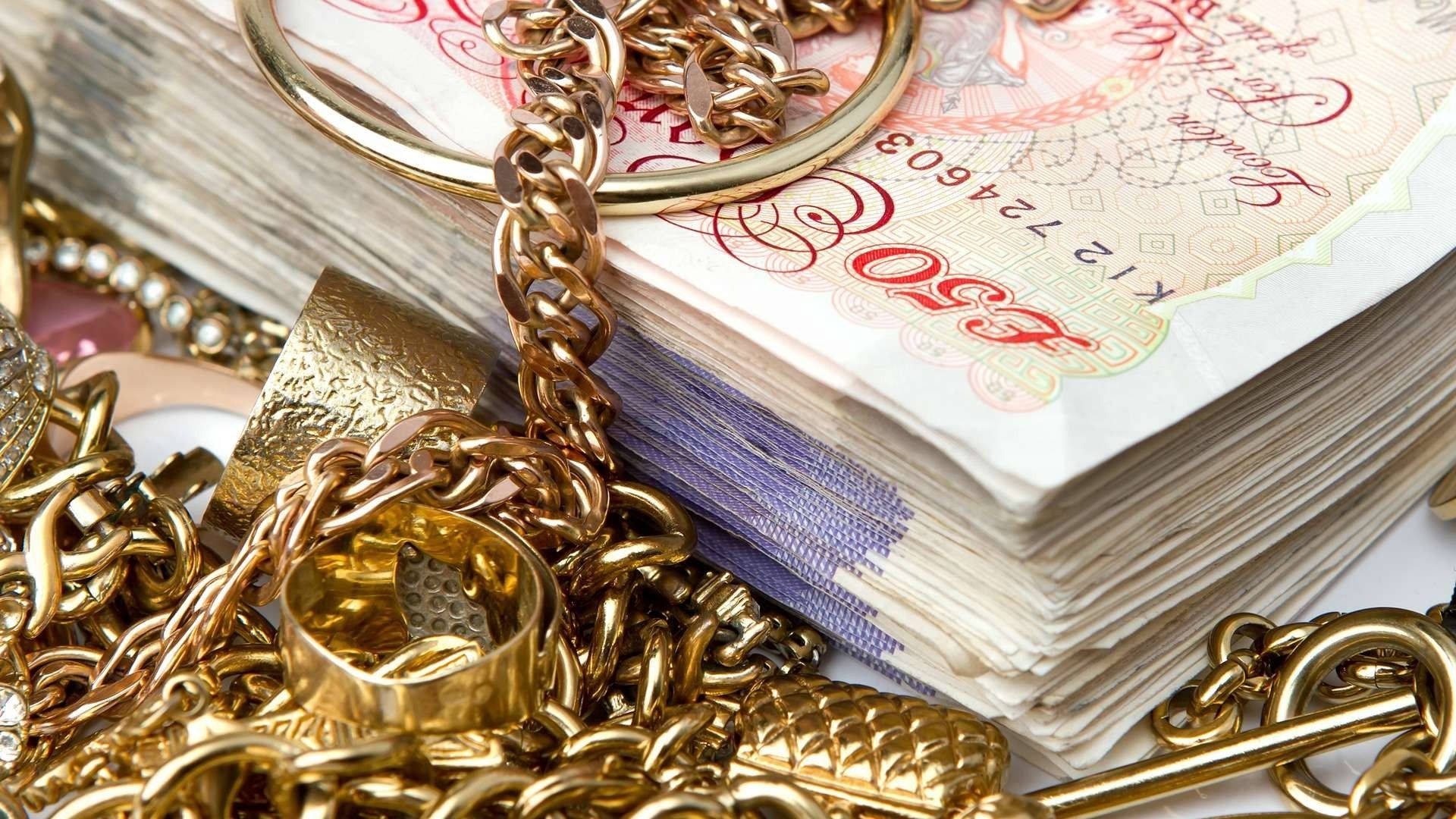 一疊英國五十英鎊紙幣，混雜著金鏈和戒指。