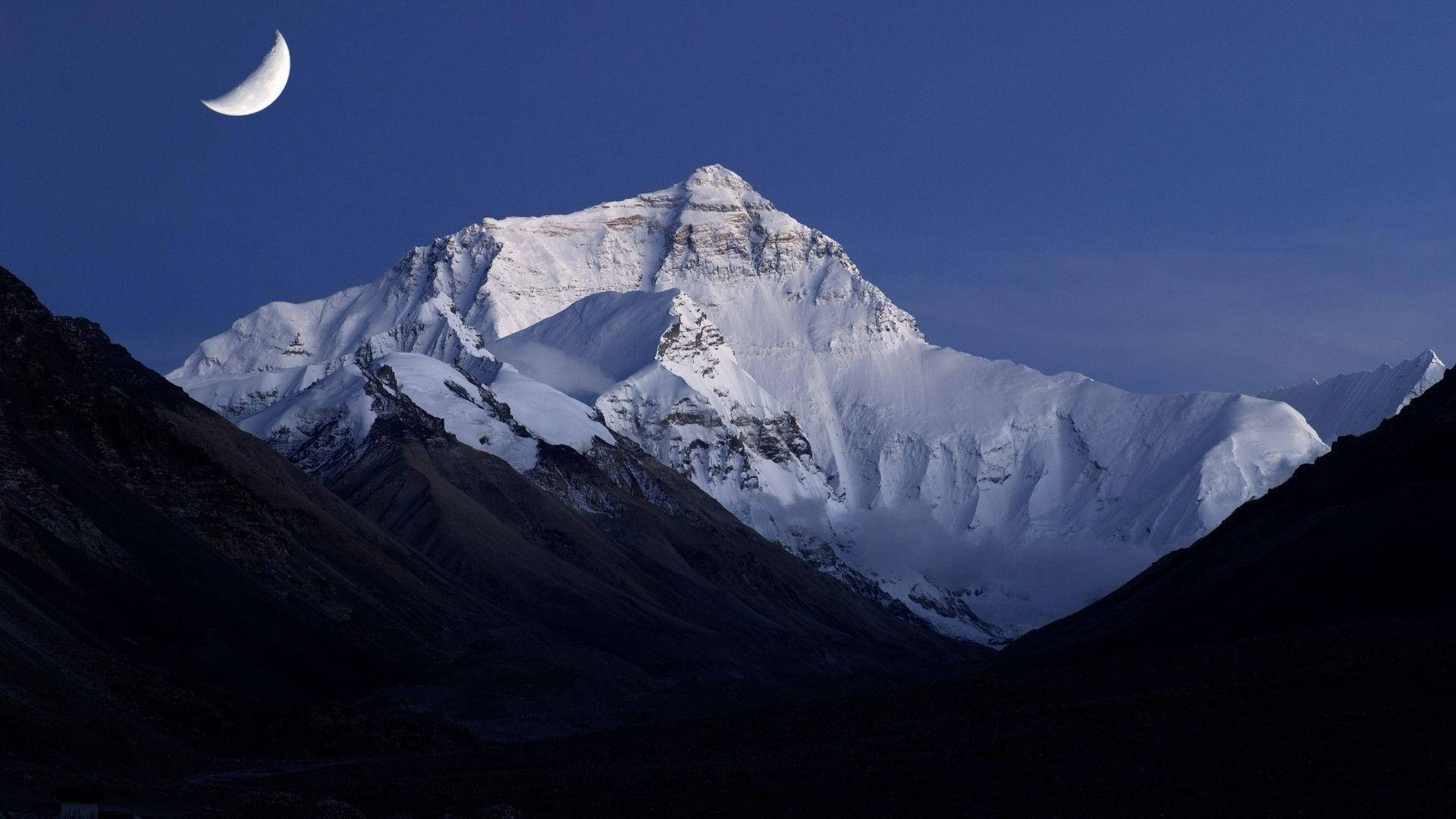 珠峰日出壯麗景色 壁紙 — 雄偉的雪山山峰在深藍色的天空下升起，一彎新月在上方閃耀。