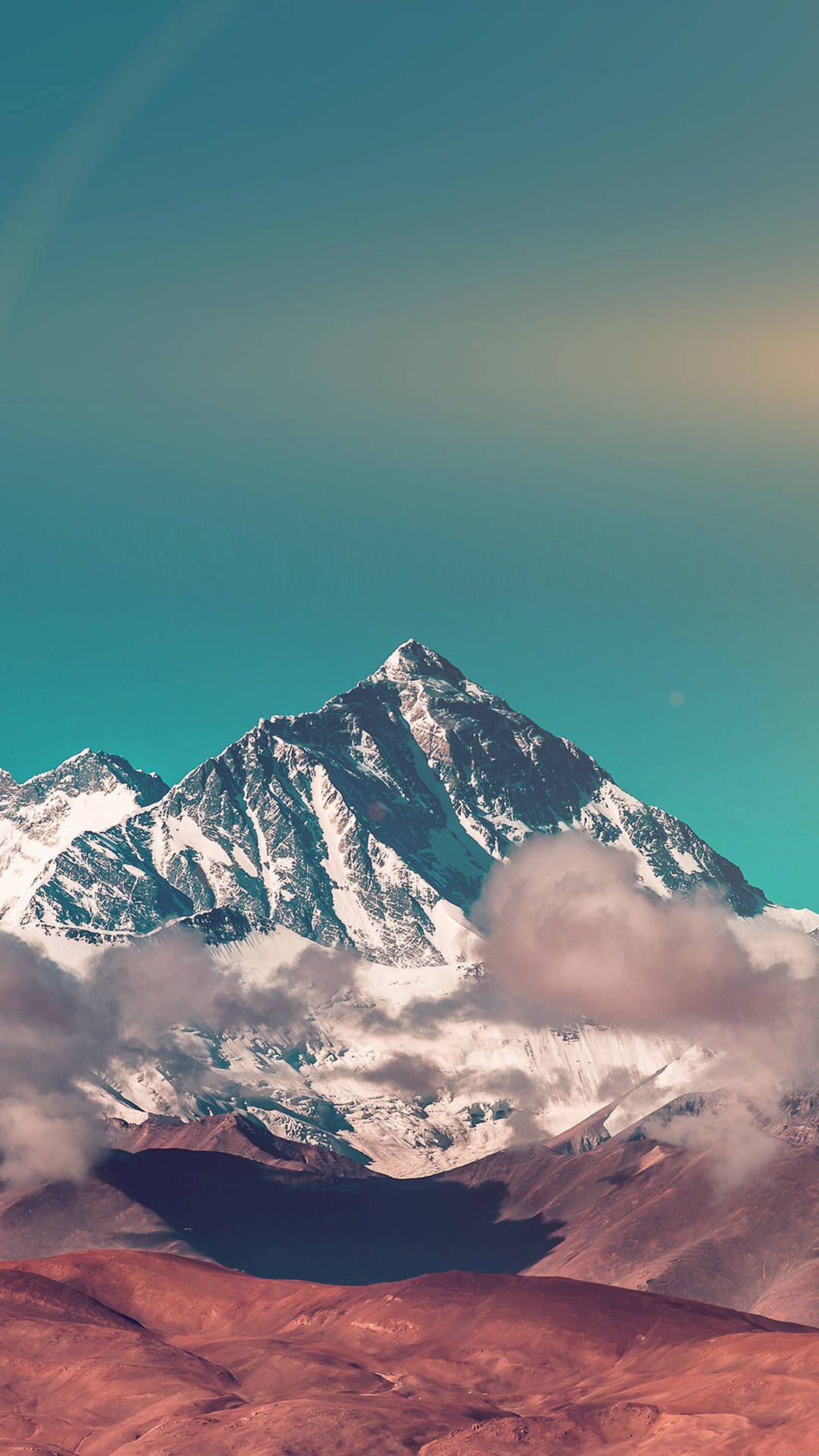 雪山山峰聳立於雲層和紅色沙漠之上，藍綠色天空