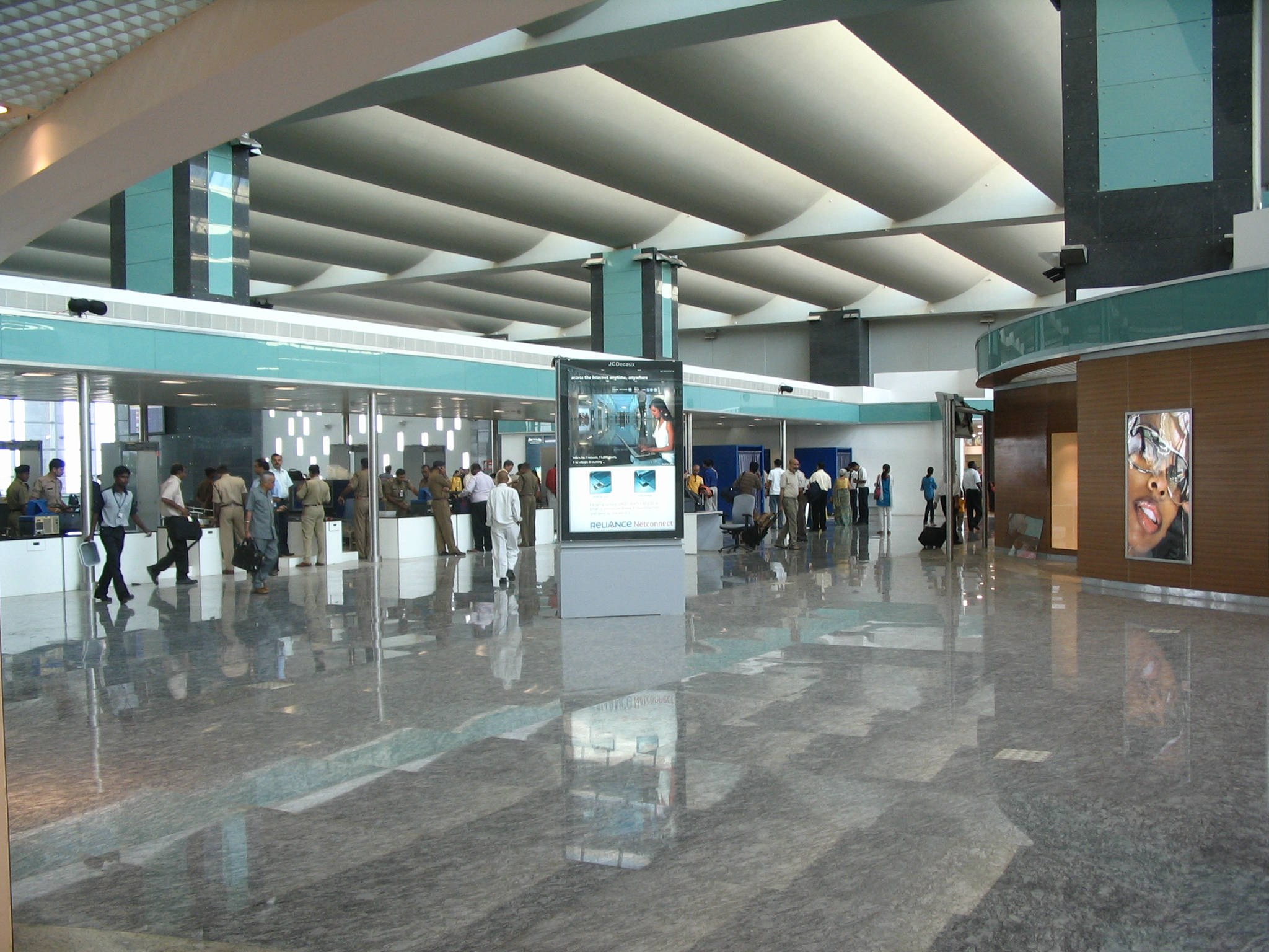 班加羅爾國際機場航廈 壁紙 — 現代機場客運大樓，旅客在幾何形天花板和反光大理石地板下經過辦理登機手續的櫃檯。