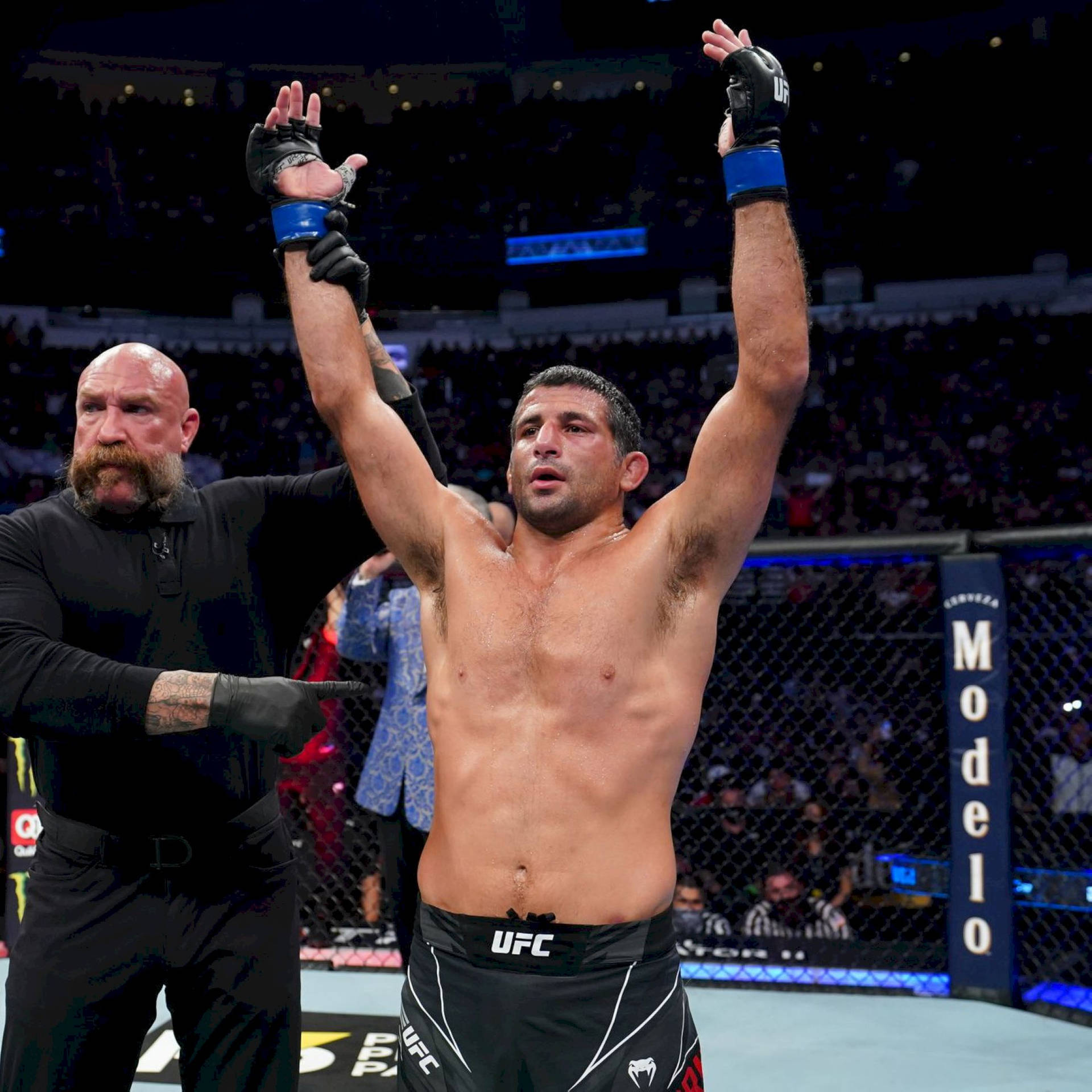 UFC拳手在八角籠內高舉雙臂慶祝勝利。