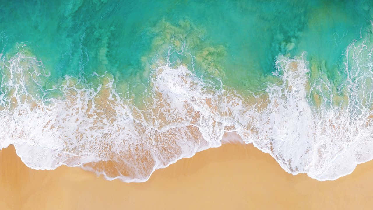 碧綠色的海浪從上方滾向金色沙灘。