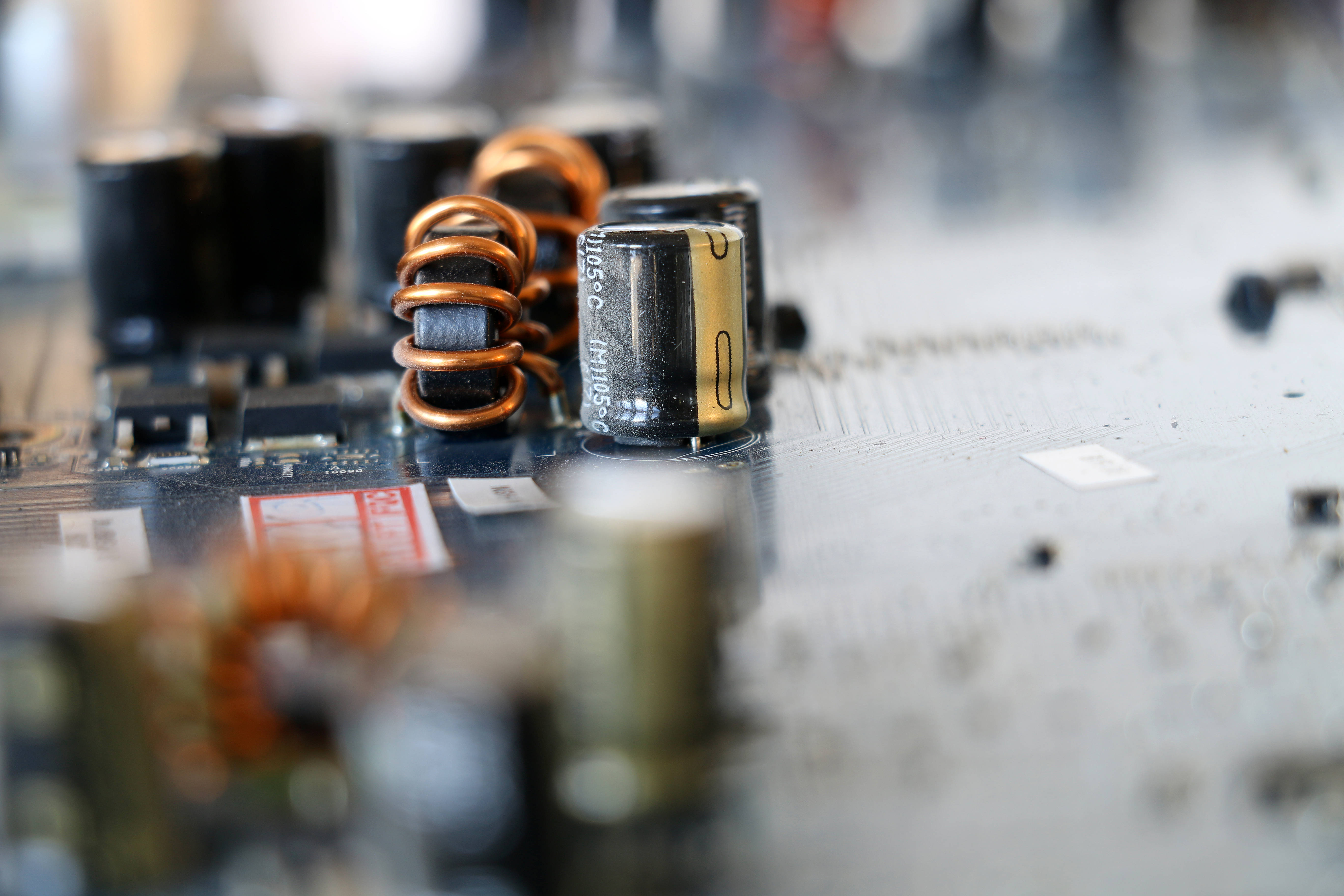 現代主機板近距離特寫 壁紙 — 電路板上銅線圈和電容器的特寫，景深較淺。