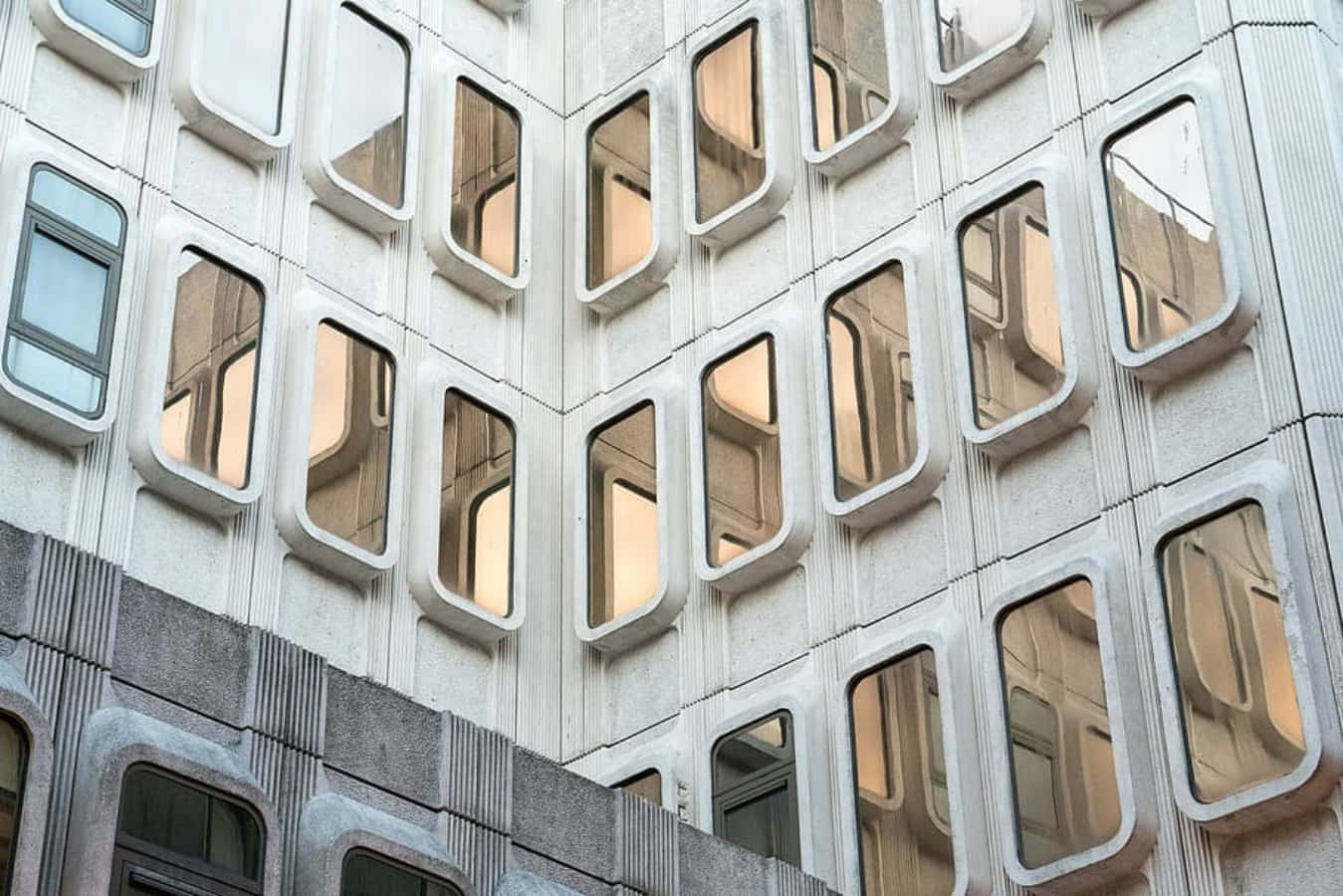 Modernism 桌布 壁紙 — 現代主義建築物外牆的特寫，帶有突出的圓形窗戶，反射溫暖的室內燈光。