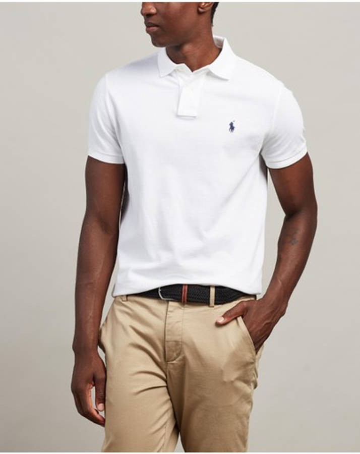 現代優雅 Ralph Lauren 白襯衫 壁紙 — 一名身穿白色Polo衫、帶有細小藍色標誌的男子，在中性背景前自信地站立。