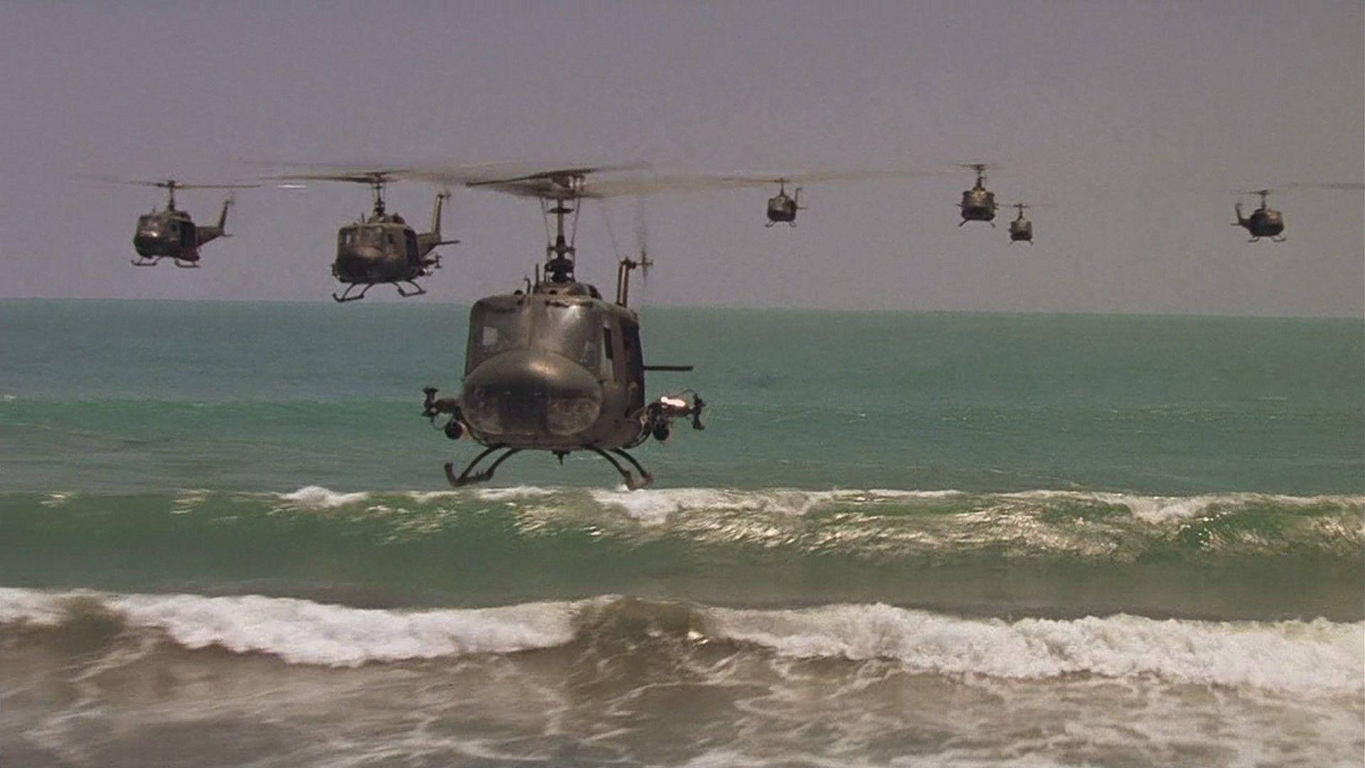 《現代啟示錄》戰鬥直升機 壁紙 — 一隊軍用直升機低飛過拍打沙灘的碧綠海浪。