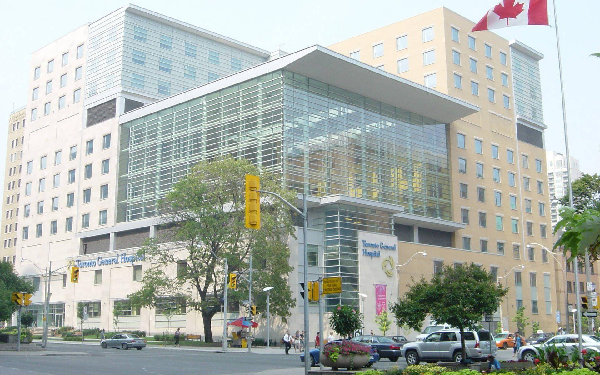 Building 桌布 壁紙 — 現代多倫多全科醫院建築，玻璃幕牆，加拿大國旗在都市環境中飄揚。