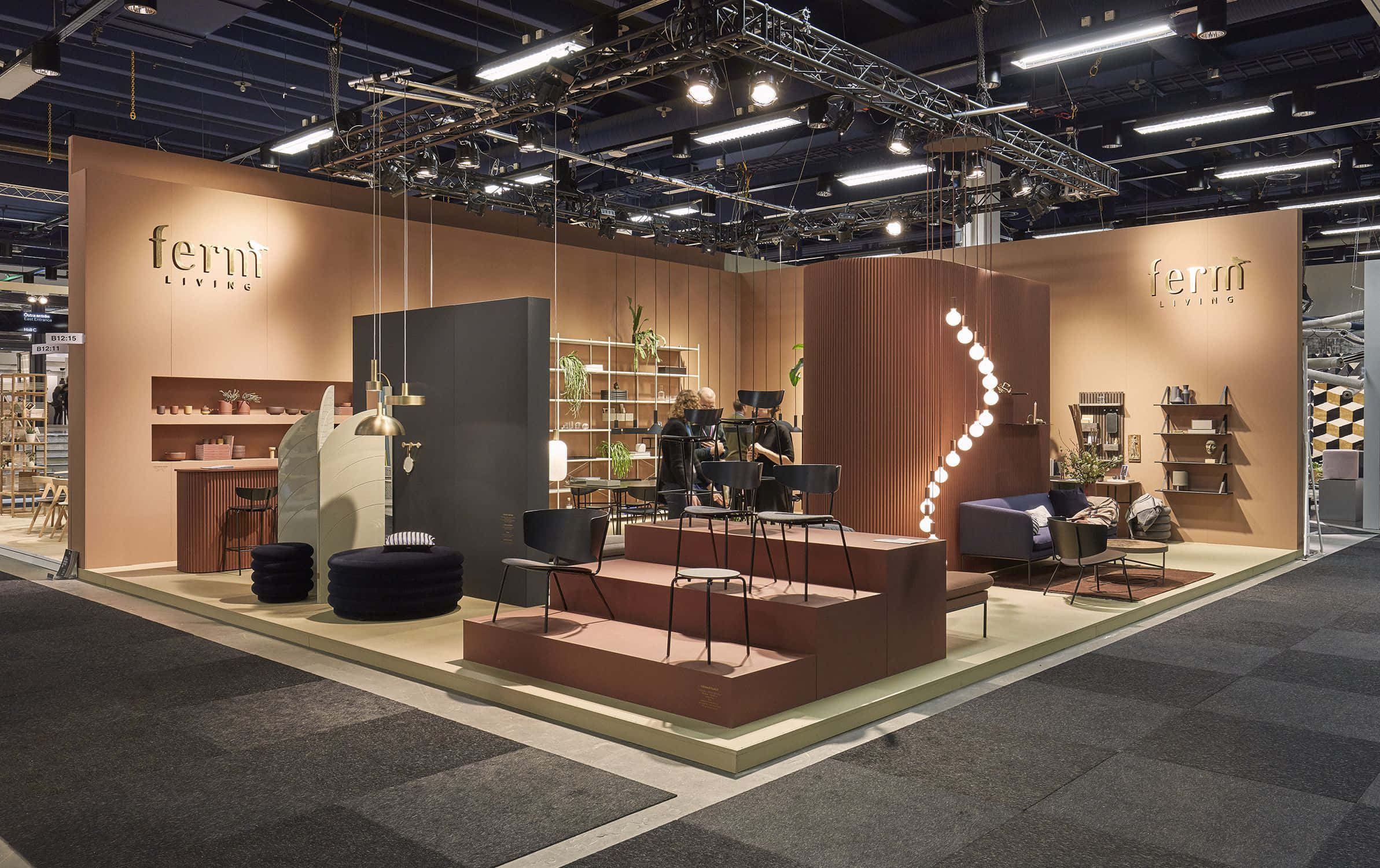 Exhibition 桌布 壁紙 — 現代家具陳列室，設有分層座位、溫暖照明和簡約裝飾，下方為裸露的工業天花板。
