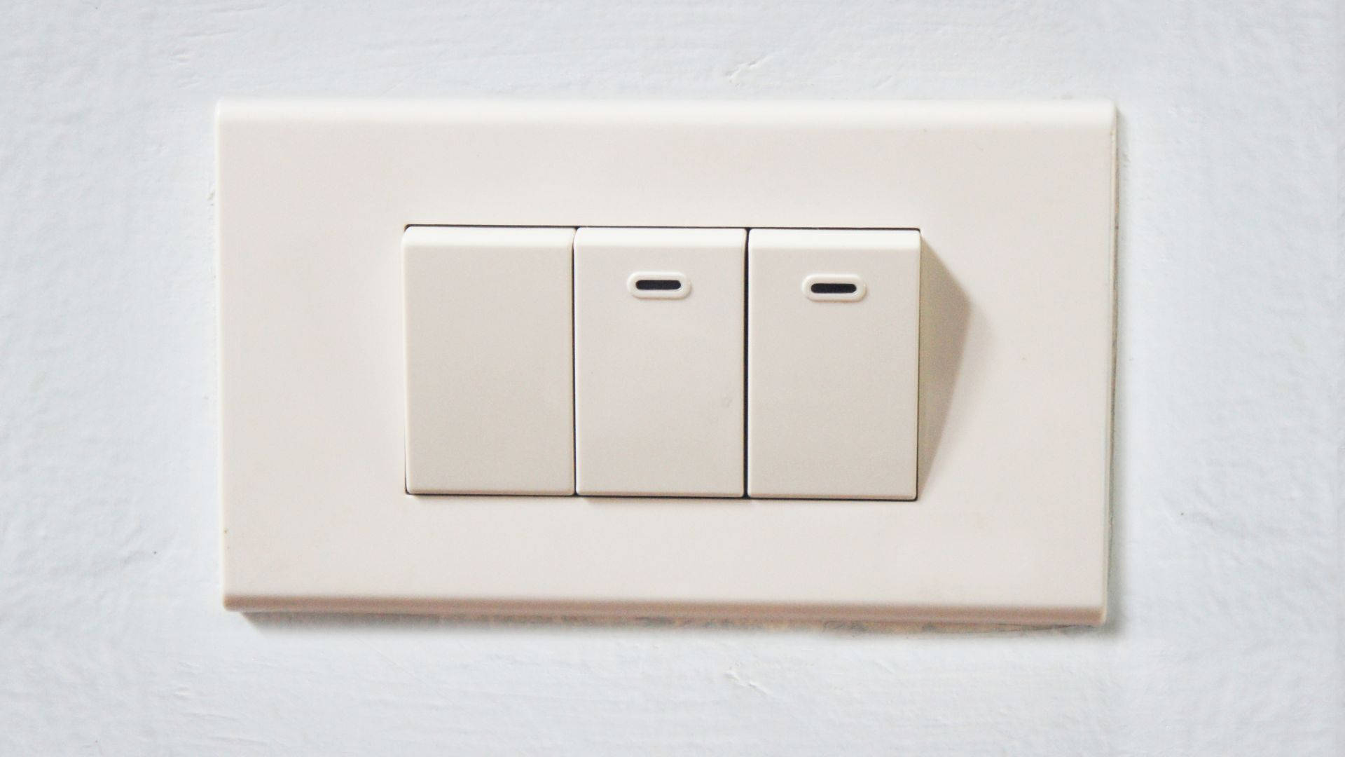 現代家居節能電源開關 壁紙 — 三個米色燈掣安裝在簡約室內設計的紋理白色牆壁上。