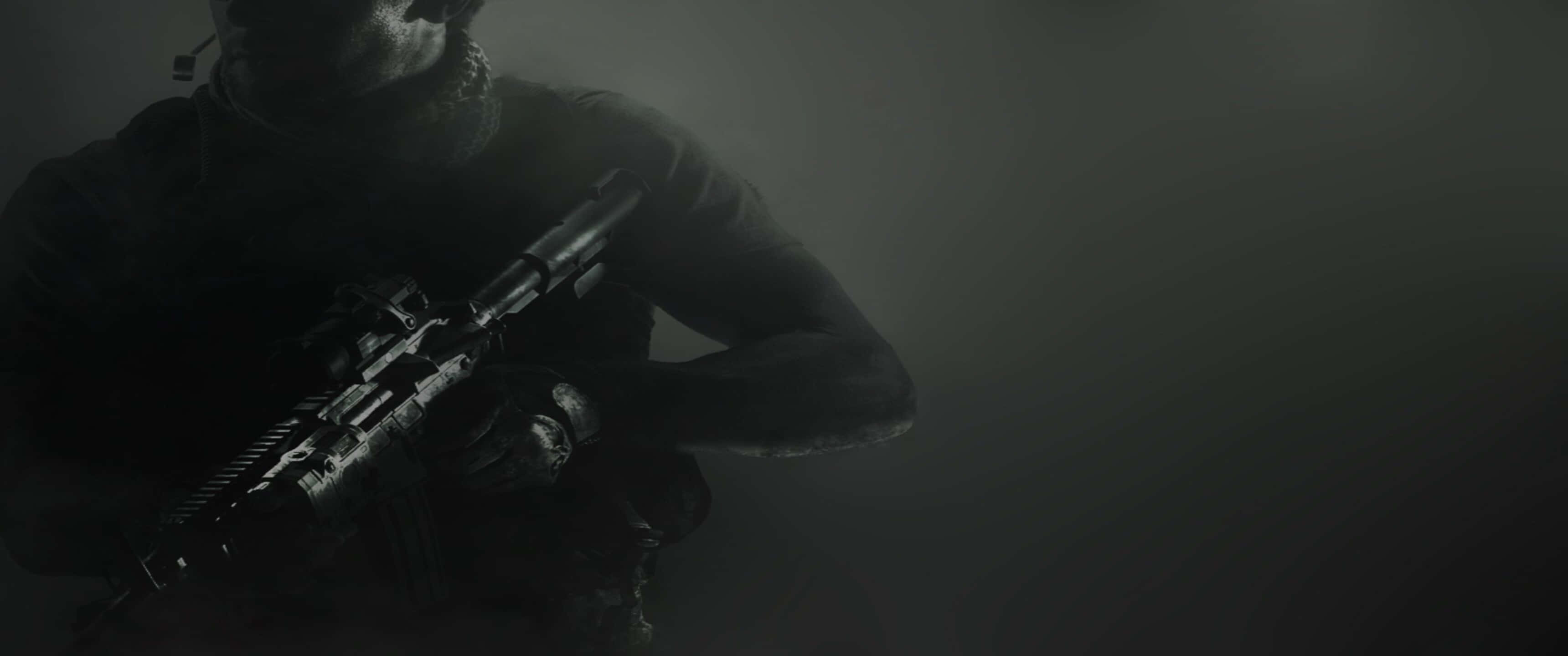 《現代戰爭》士兵持槍特寫壁紙 3440x1440p 壁紙 — 一個陰影般的士兵穿著戰術裝備，在昏暗、煙霧瀰漫的環境中握著步槍，色調柔和灰暗。