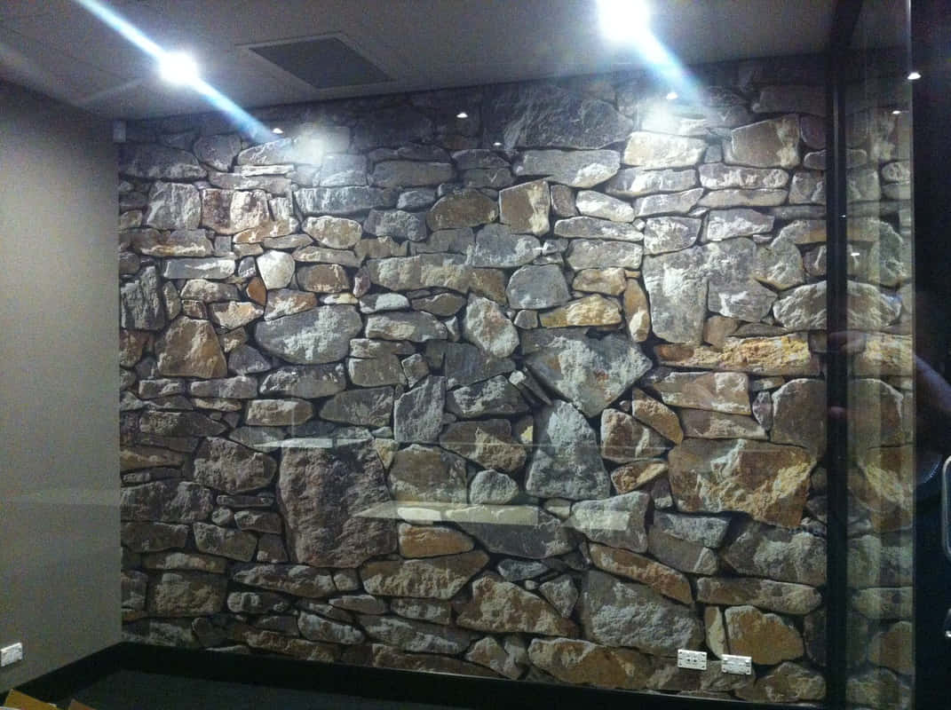 Installation Art 桌布 壁紙 — 現代房間中，在明亮天花燈光下，帶有各種灰色、棕色和棕褐色石頭的紋理石牆壁紙。