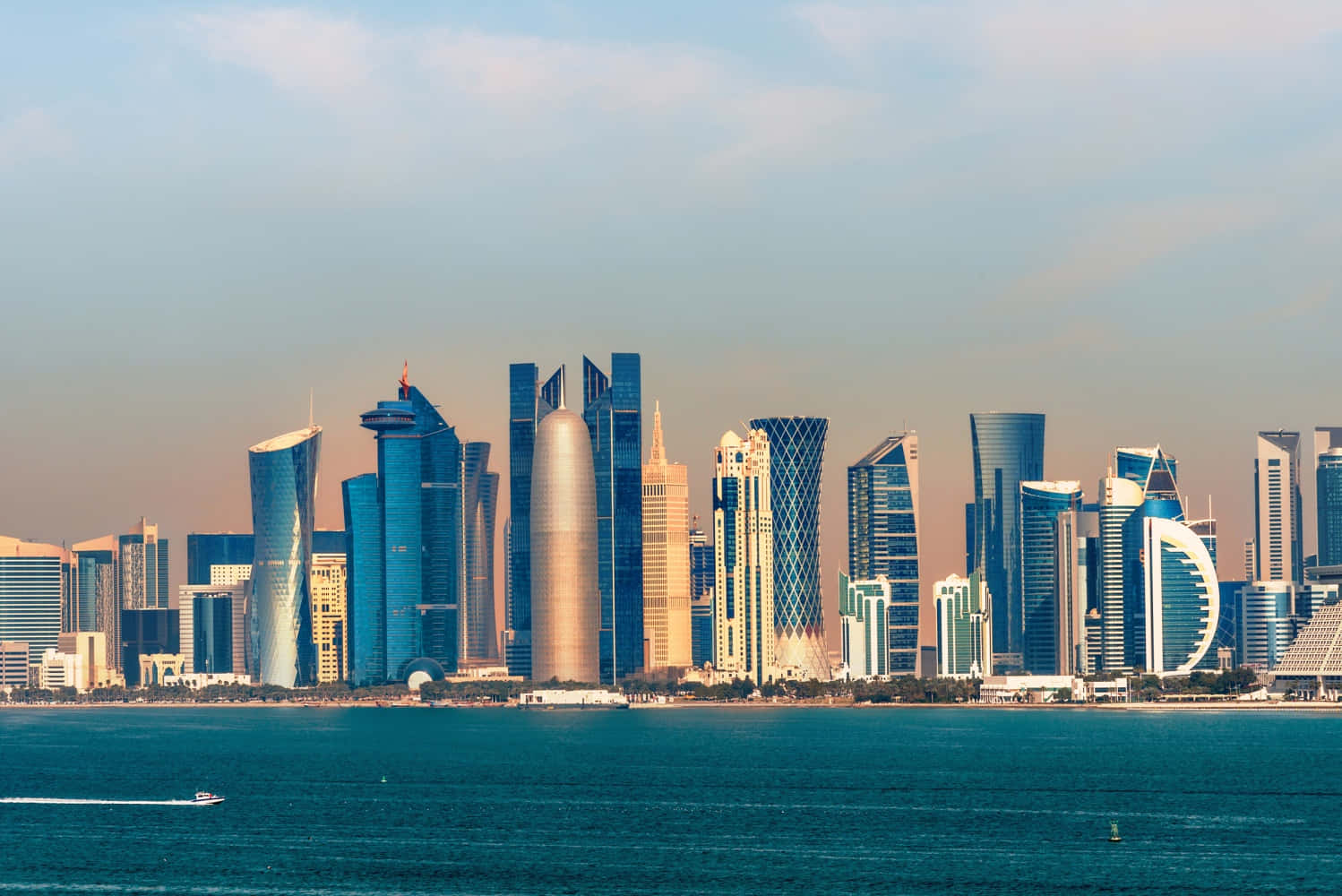 Qatar 桌布 壁紙 — 現代摩天大樓以藍色和金色外牆從平靜的海面升起，在柔和天空下。