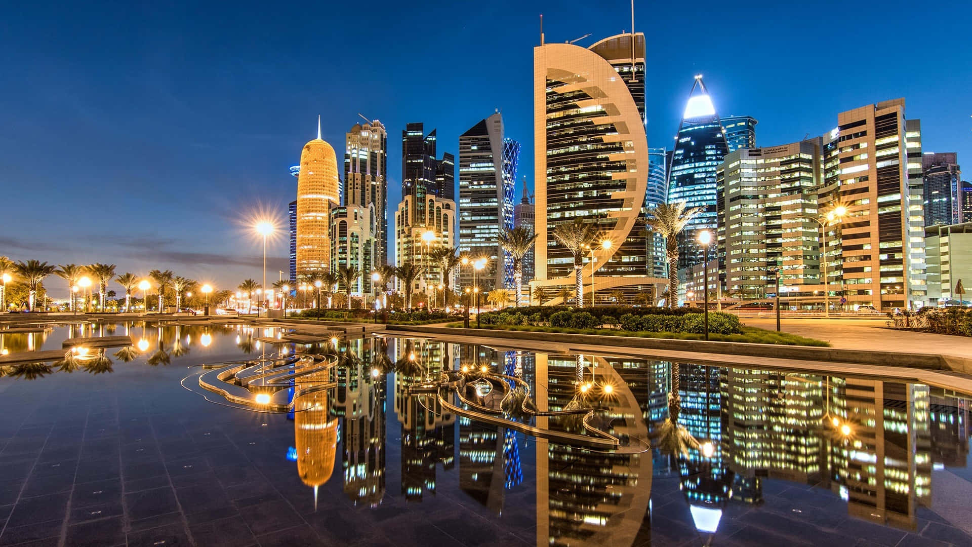 Qatar 桌布 壁紙 — 現代摩天大樓的壯麗夜景，璀璨燈光倒映在平靜的水面上。