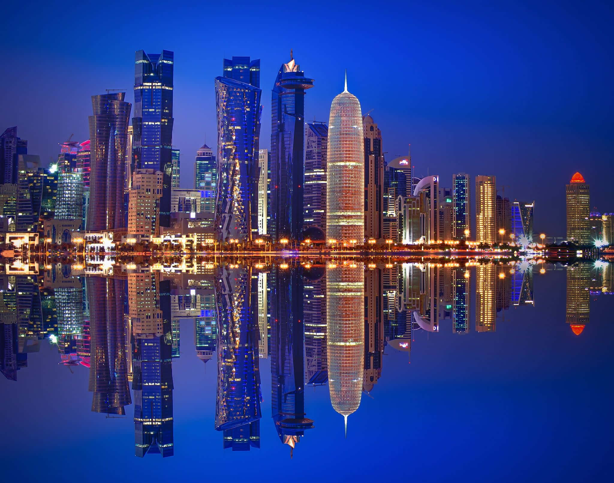 Qatar 桌布 壁紙 — 現代摩天大樓的迷人夜景，鮮豔燈光完美倒映在平靜的水面上。