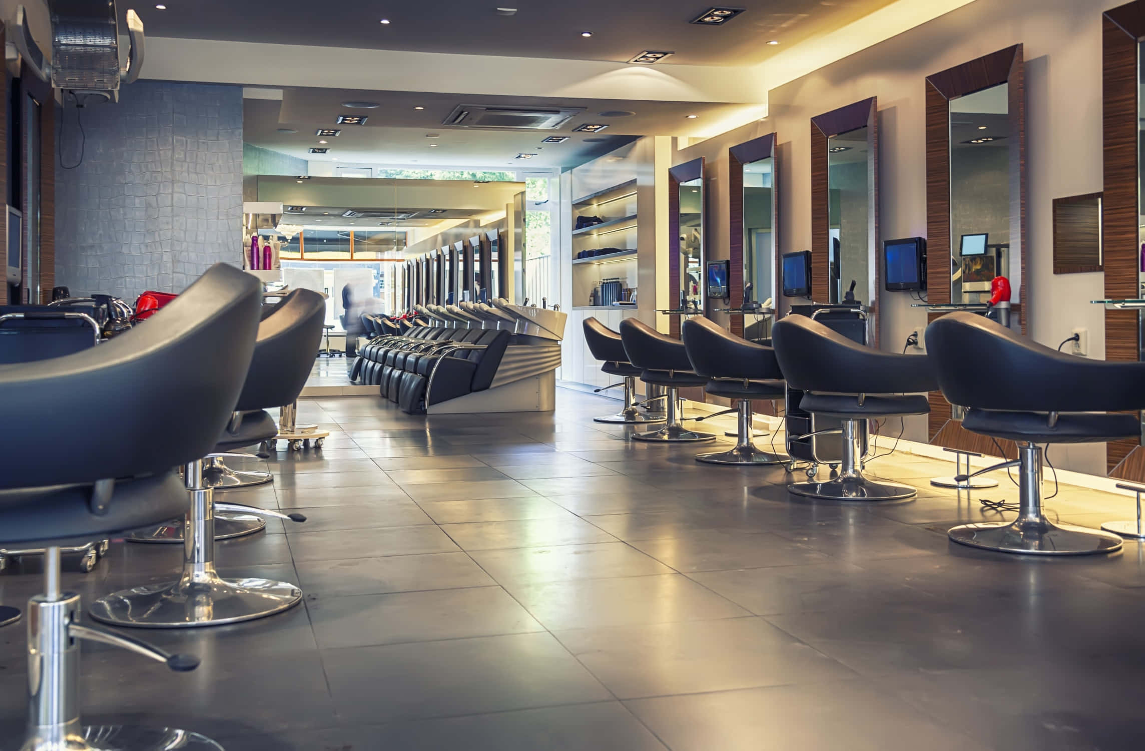 Hair Salon 桌布 壁紙 — 現代時尚沙龍，在溫暖的環境燈光下排列著黑色造型椅和鏡子。