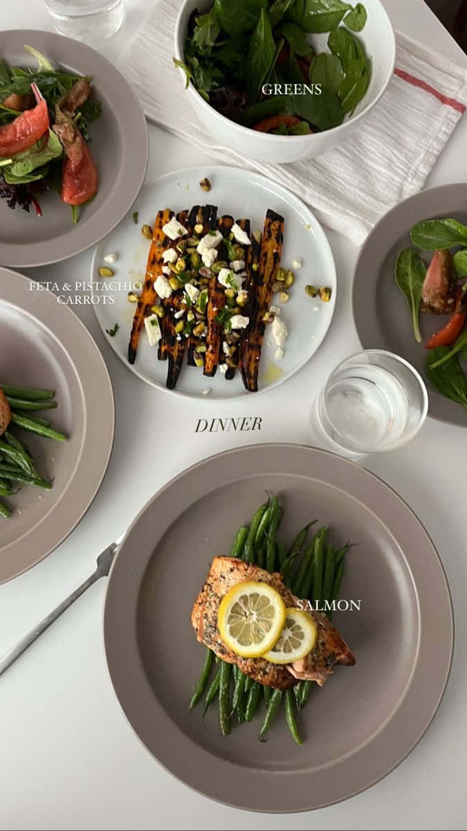 Minimalist Food 桌布 壁紙 — 現代晚餐桌的俯視圖，三文魚、青豆、烤紅蘿蔔和沙律放在柔和的灰色碟上。