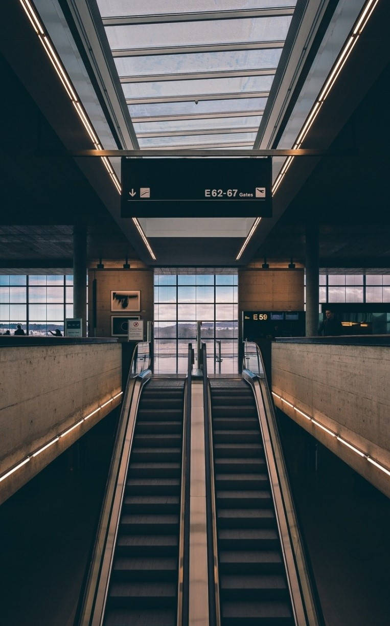 Airport 桌布 壁紙 — 現代機場客運大樓，設有通往登機閘口的自動梯，上方為玻璃天花，大窗戶展示暮色天空。