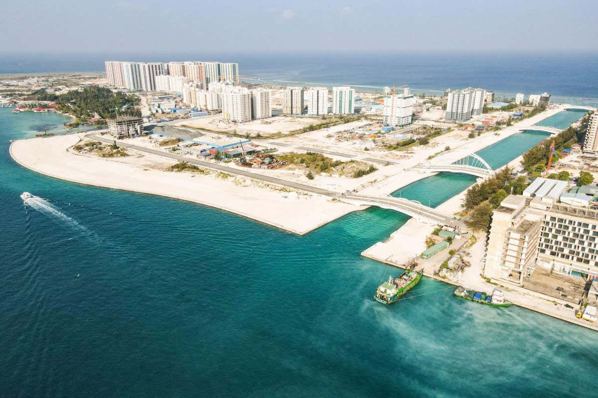 Maldives Island 桌布 壁紙 — 現代沿海城市的鳥瞰圖，擁有碧綠海水、白色沙灘和藍天白雲下的高層建築。