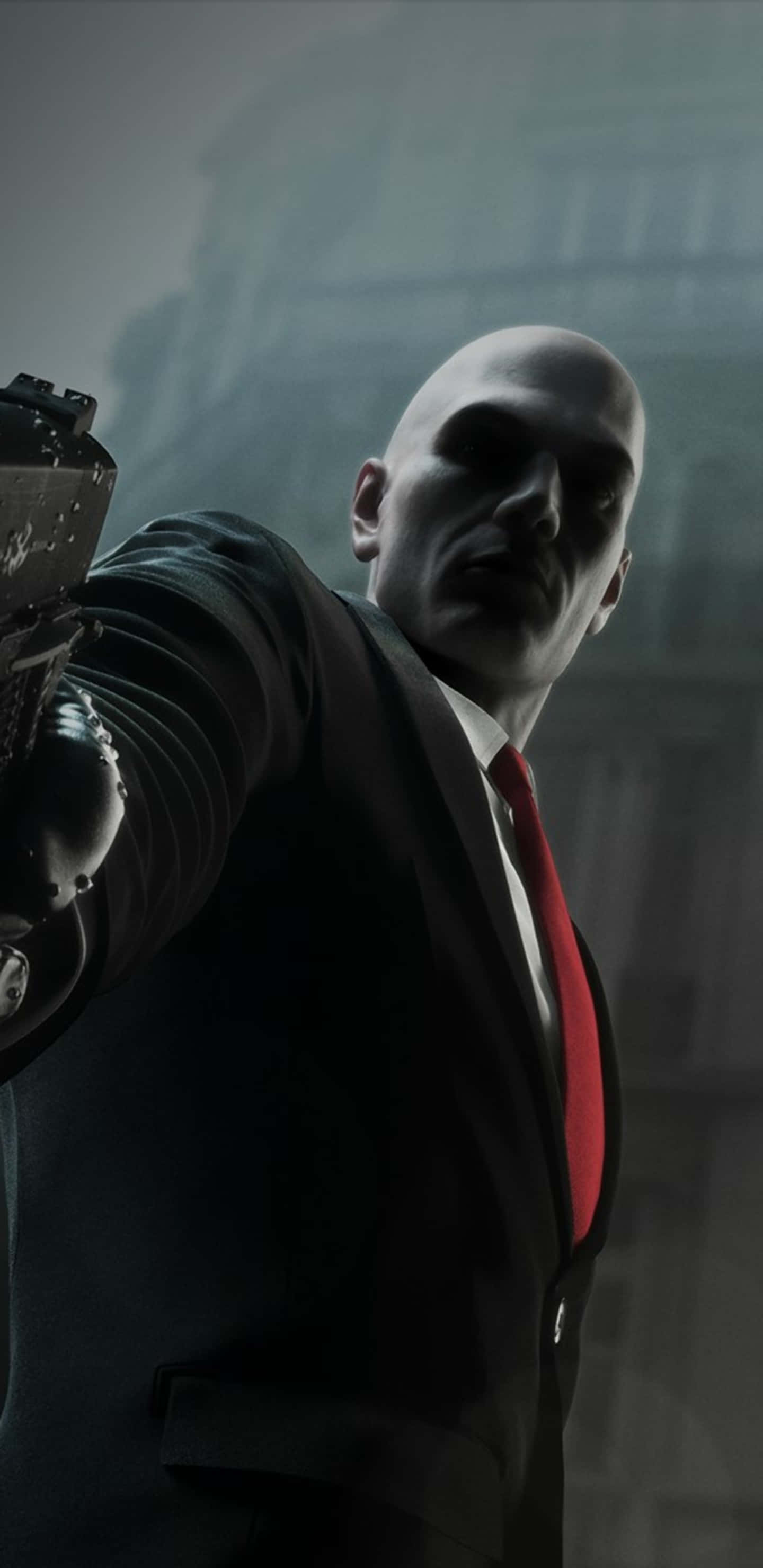 現代版經典 Hitman 壁紙 — 一個光頭男子身穿深色西裝和紅色領帶，在模糊的城市背景下，表情陰沉地向前瞄準手槍。